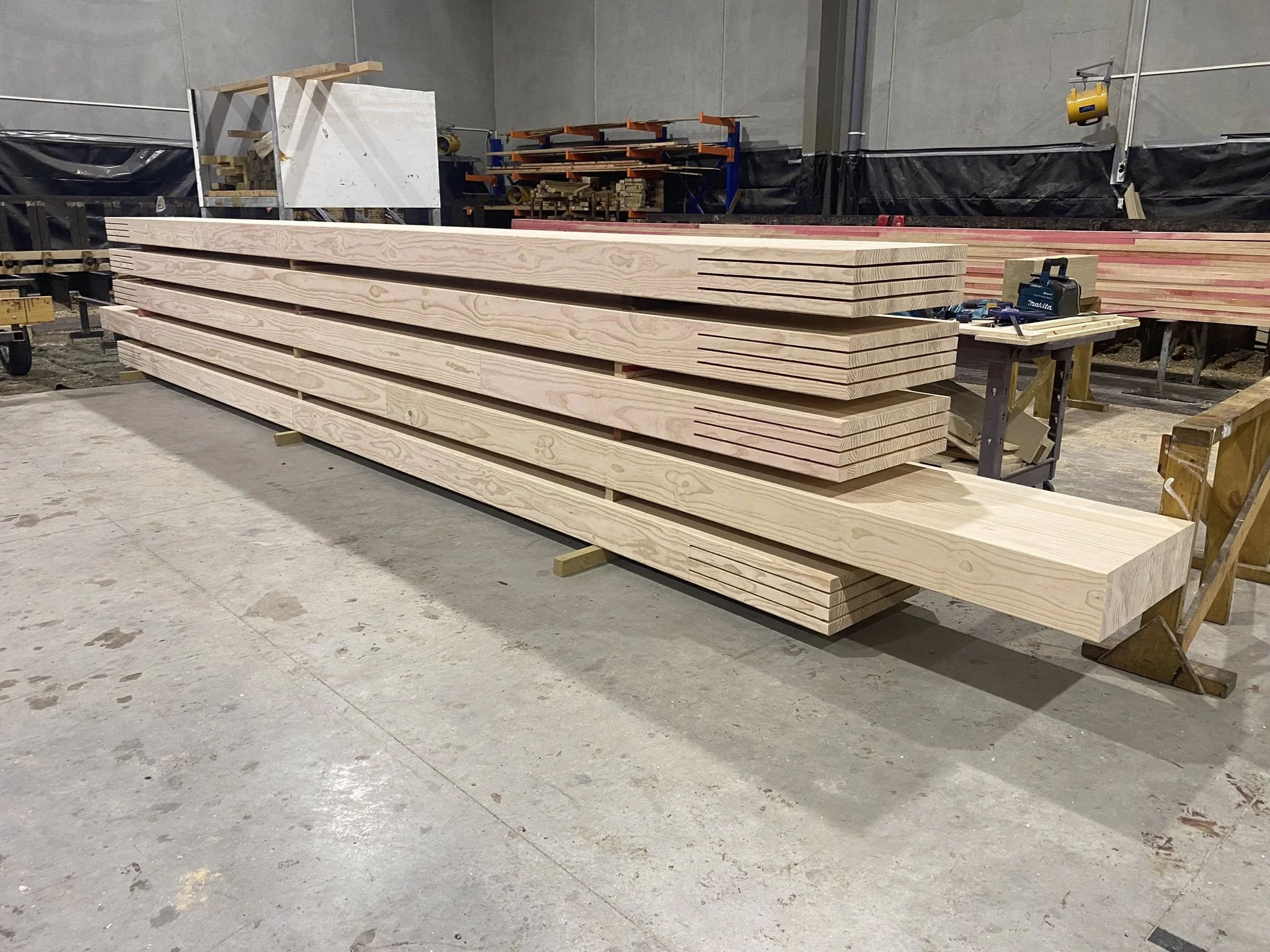 Stacks of wooden planks and construction tools in a warehouse or workshop.