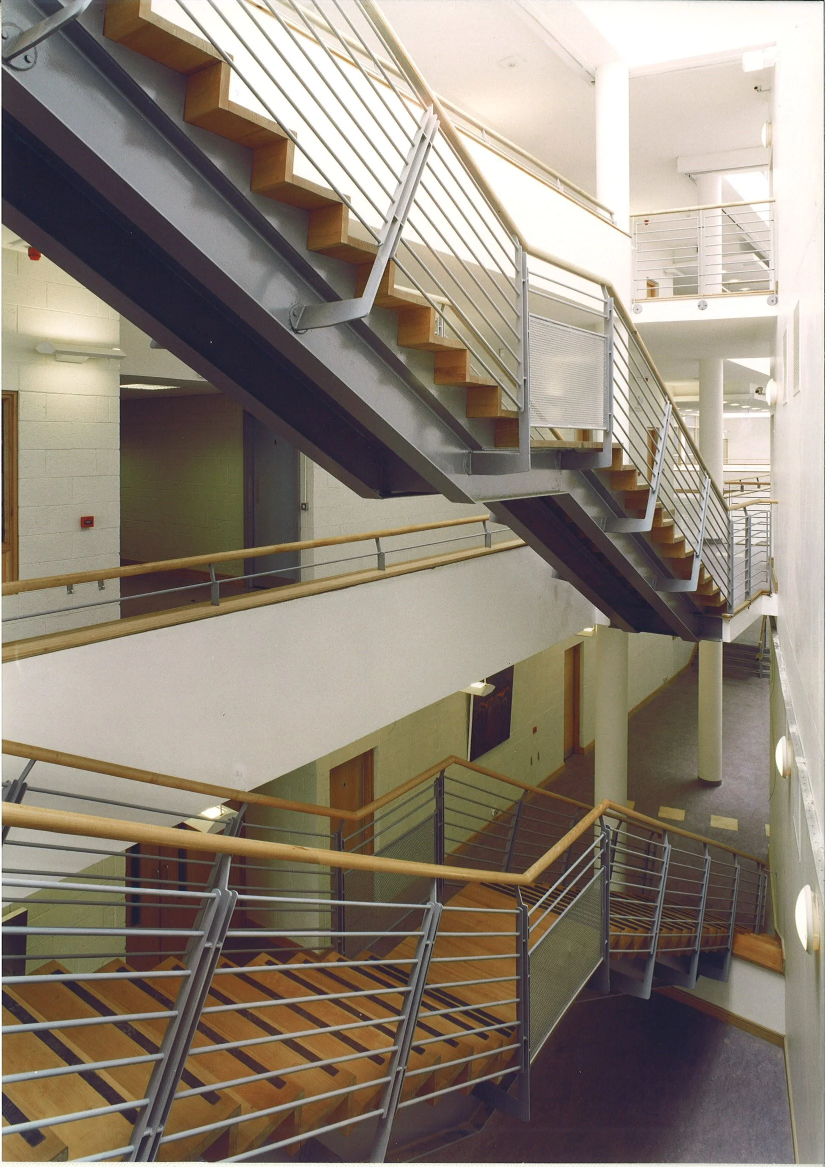 Interior view of a modern multi-story building with metal and wooden staircases and walkways connecting different floors.