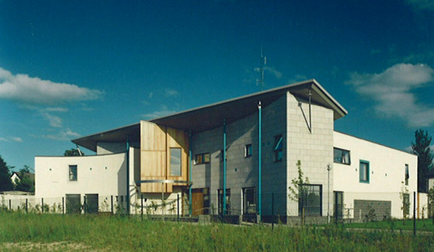 Modern multi-story house with a unique architectural design, wood accents, and a well-maintained lawn under a partly cloudy sky.