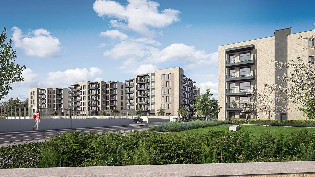 Modern apartment buildings with balconies, set against a bright blue sky with scattered clouds. There are trees, grassy areas, and a few people walking outside.