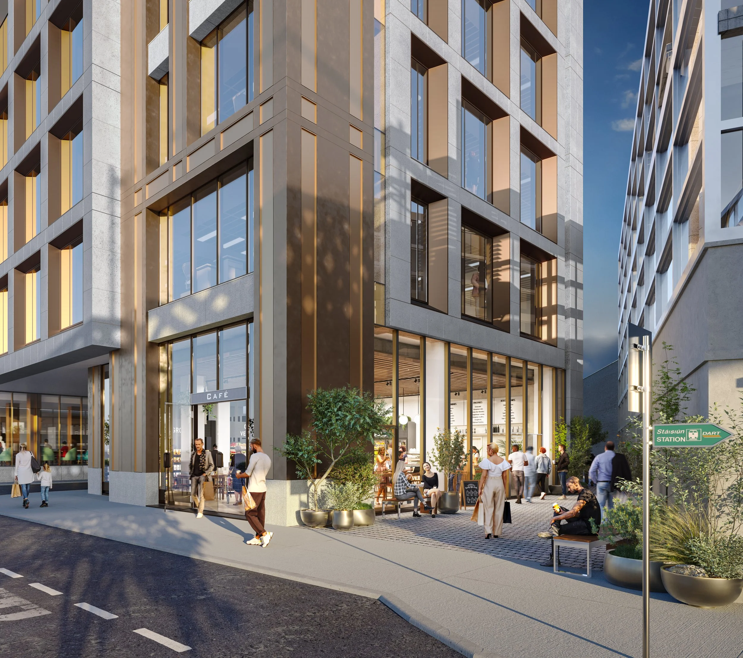 People sitting and walking outside a modern city building with a café and a station sign.