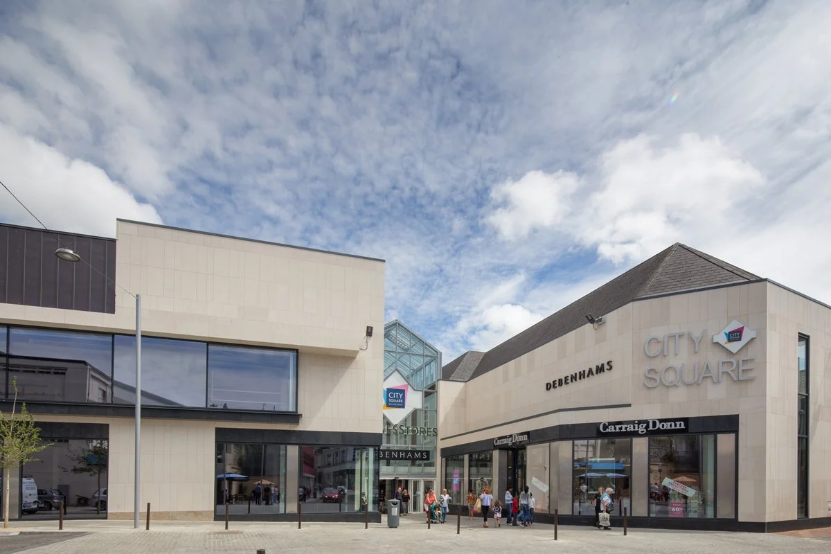 City Square shopping mall entrance with stores, signs, and people walking outside.