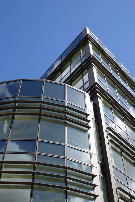 Close-up of modern glass building with reflective windows and a clear blue sky.