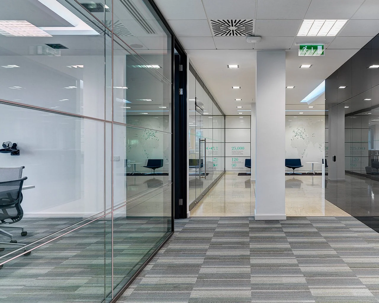 Empty modern office waiting area with glass walls and chairs.