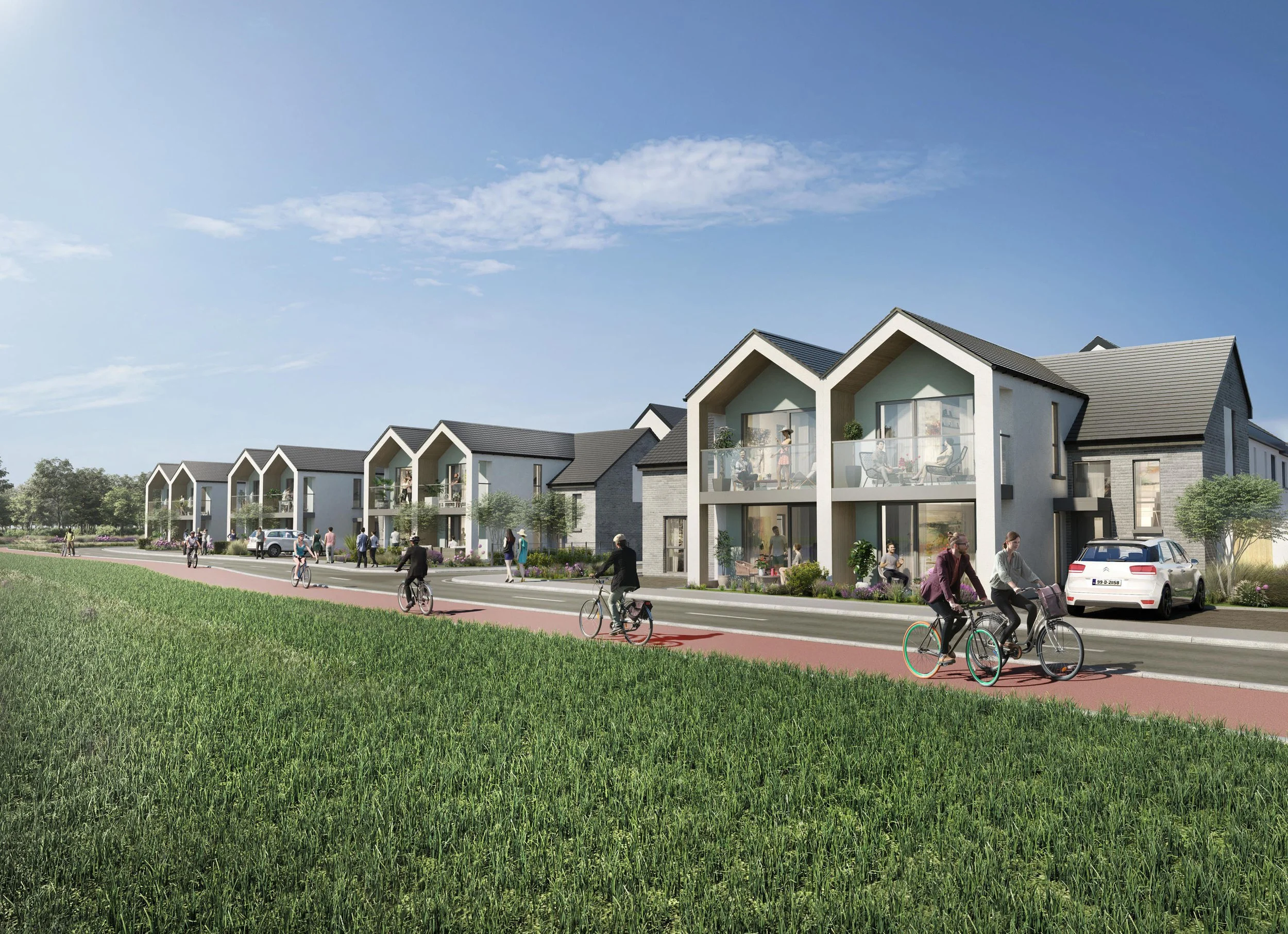 Modern residential buildings with glass balconies, residents walking and biking along a street, and a grassy field in foreground under a clear blue sky.