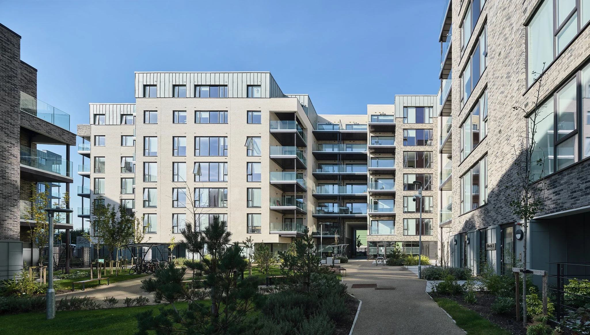 Modern residential apartment complex with landscaped courtyard and walkways during daytime.