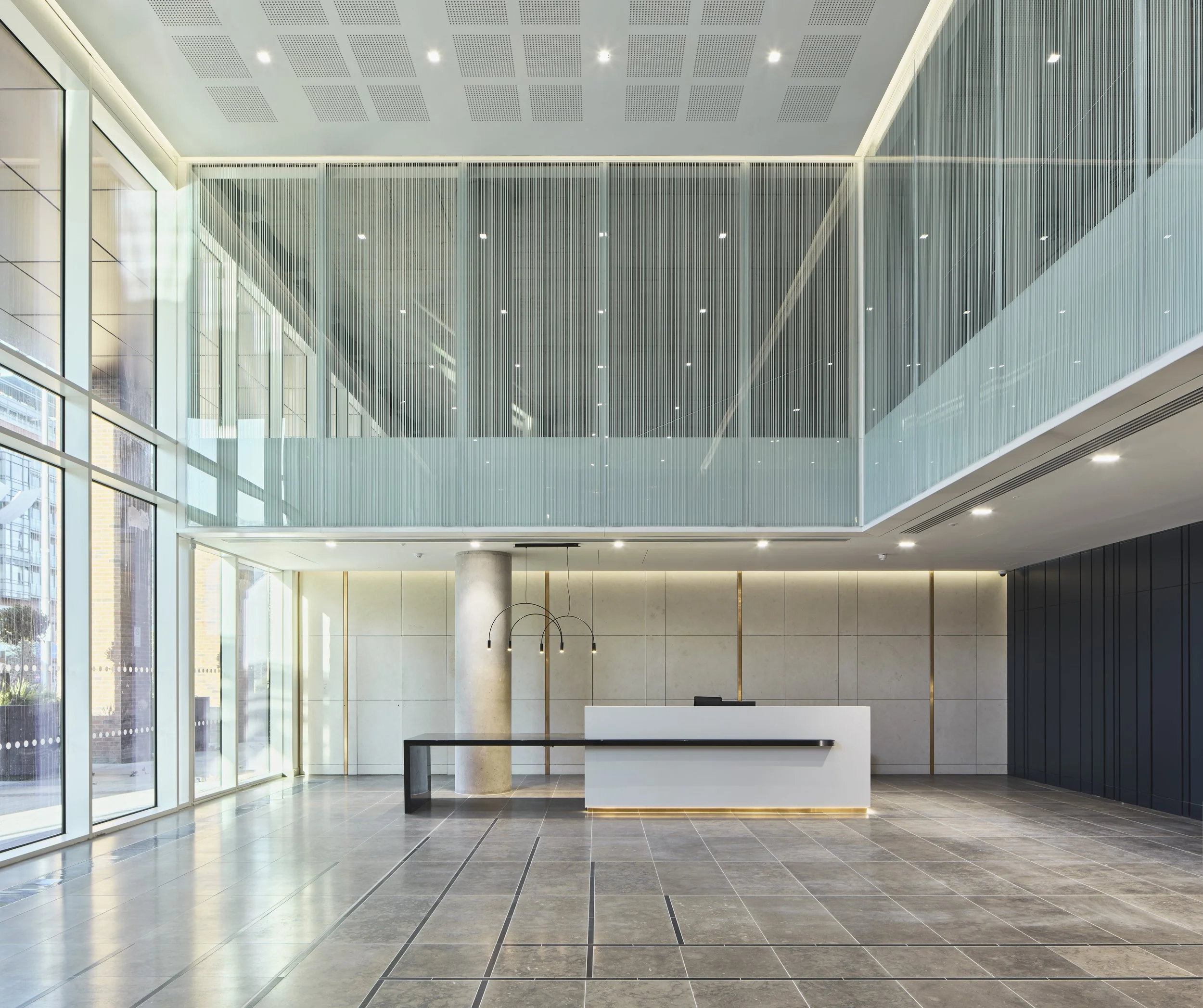 Modern office lobby with glass walls, a white reception desk, and minimalistic decor.