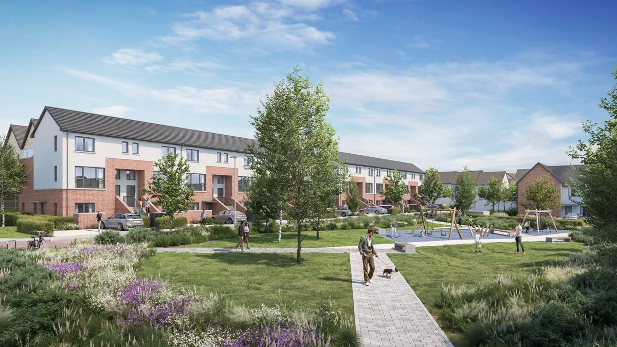 A modern residential complex with multiple townhouses, a landscaped communal garden with trees and flowering plants, and a playground with children playing and adults walking a dog.