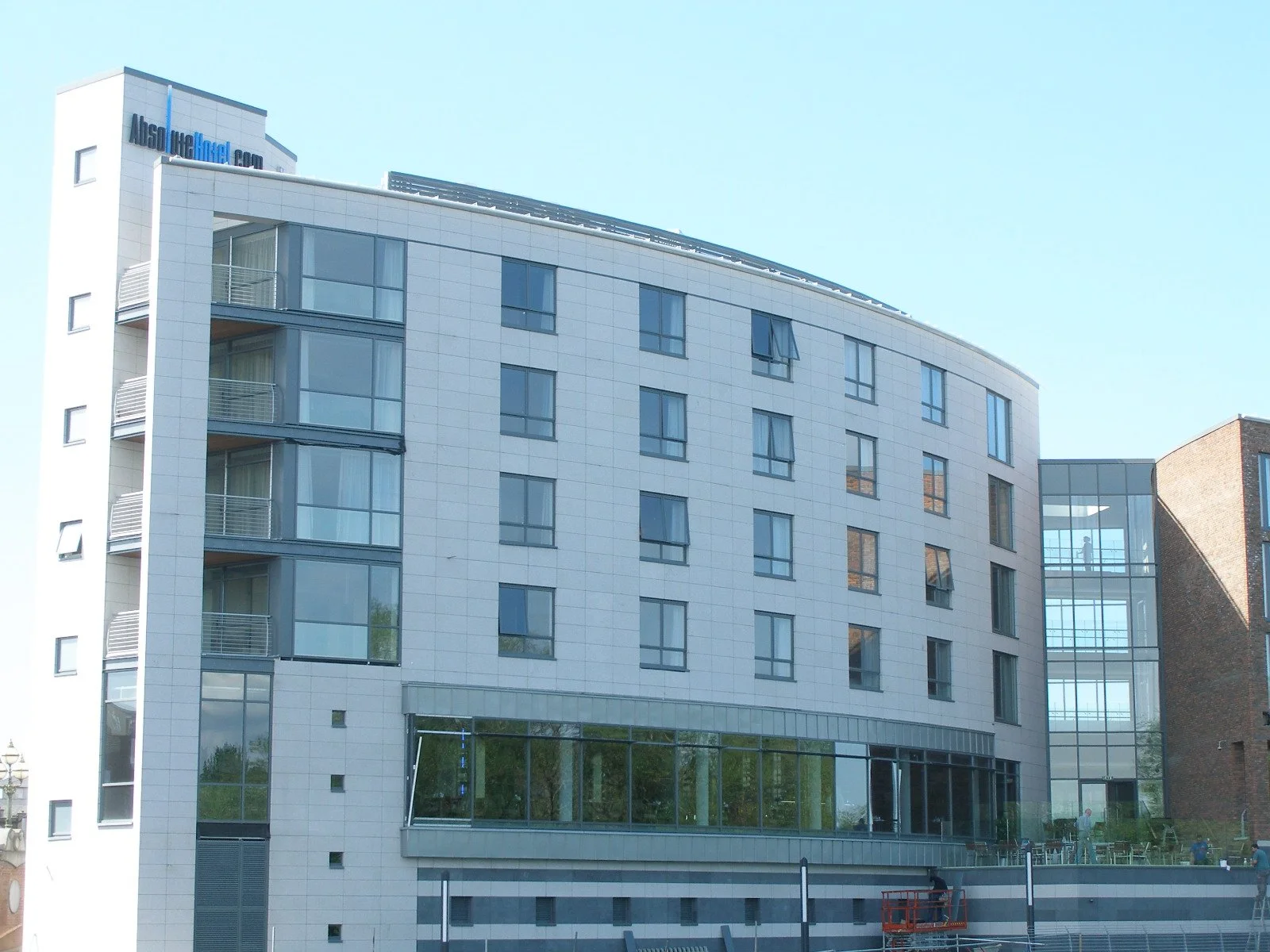 A modern multi-story office building with large glass windows and a curved white exterior, featuring a rooftop sign that reads 'Also good local.'