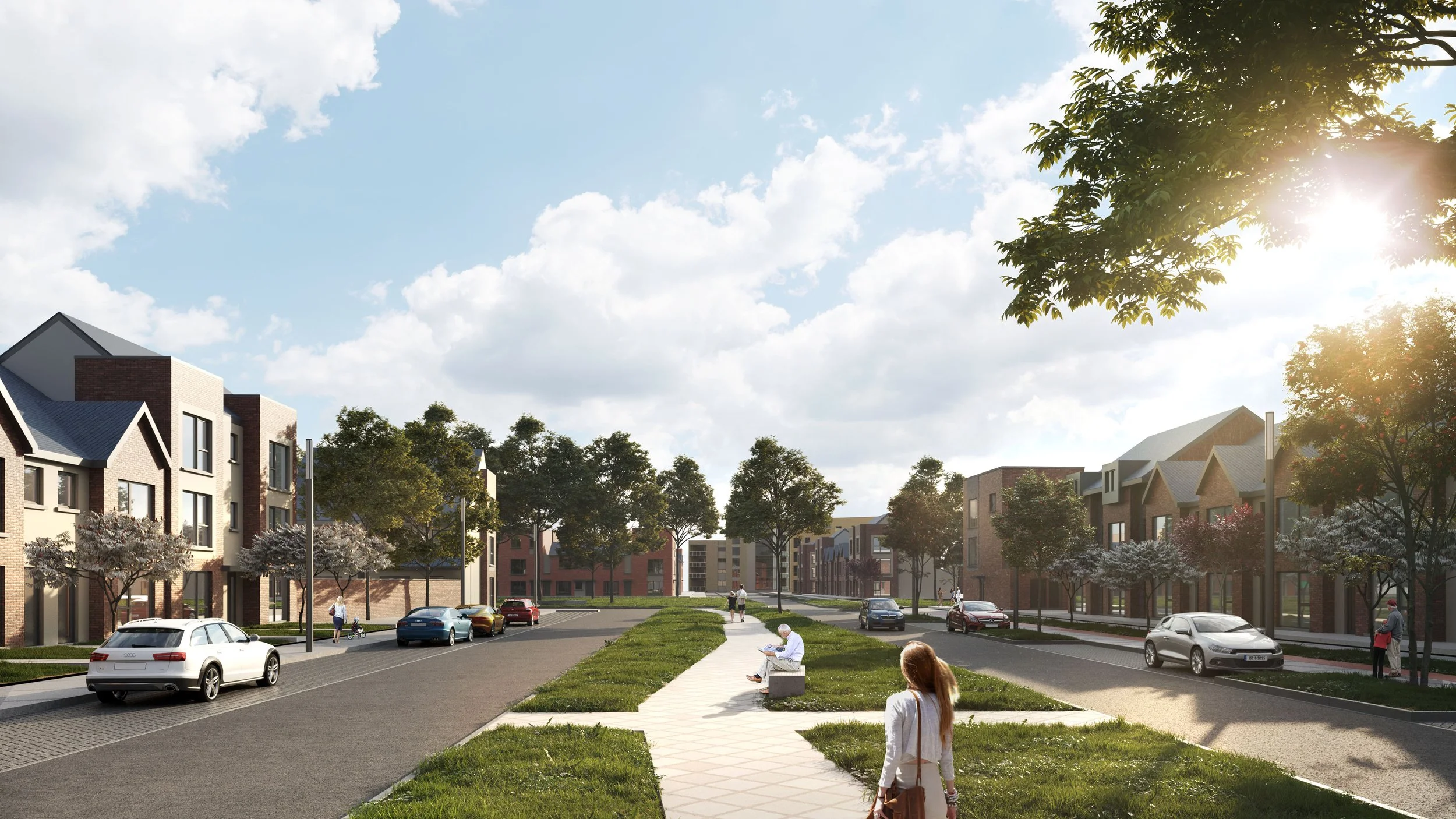 A suburban street with modern houses on both sides, trees, a paved sidewalk, grassy strips, and several cars parked along the street. People are walking and sitting, with sunlight shining through the trees.