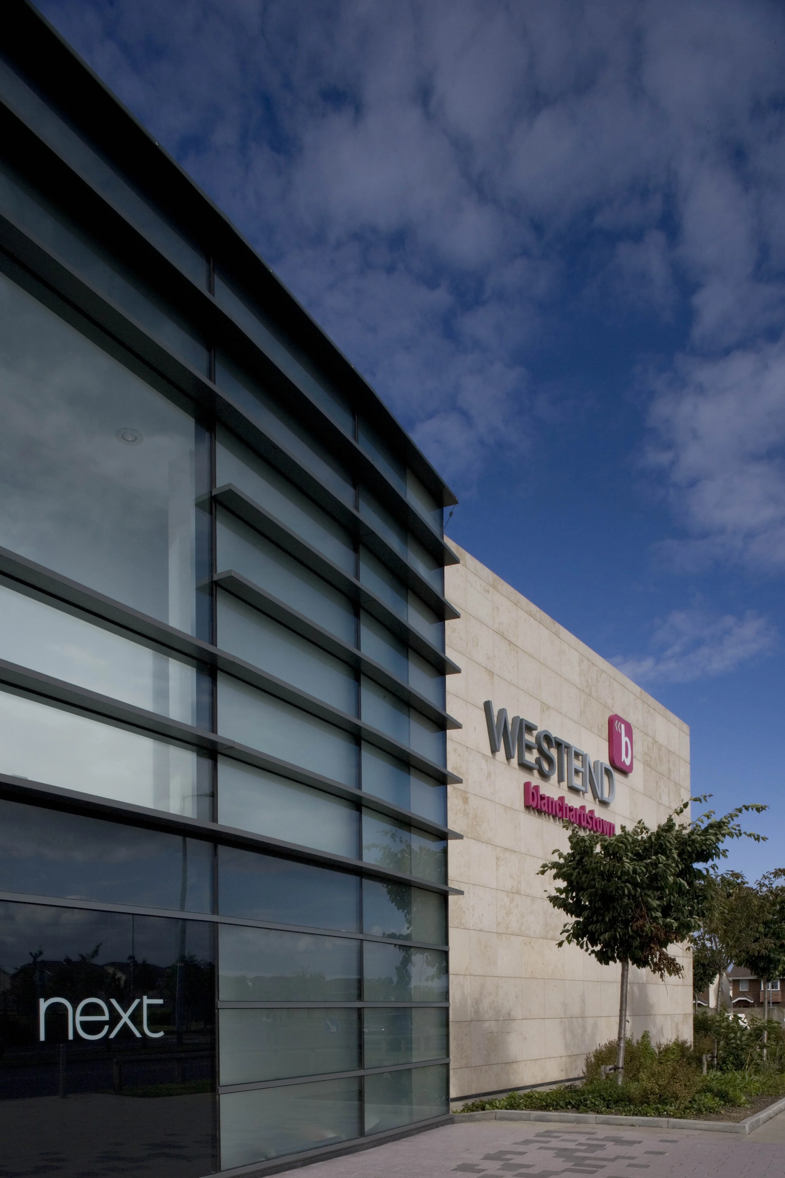 Exterior view of Westfield Blanchet Town shopping mall with glass windows, signage, and a small tree in front.