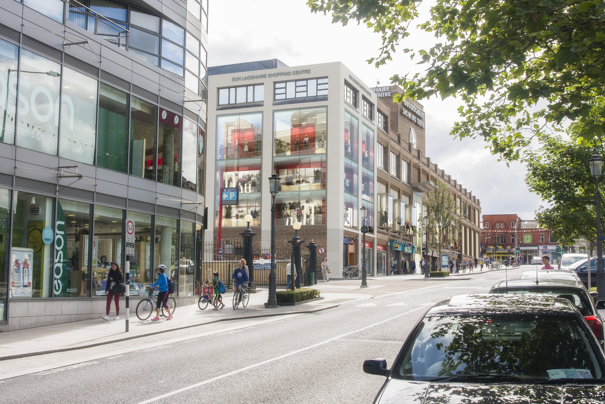 City street scene with modern commercial buildings, pedestrians, cyclists, parked cars, and trees.