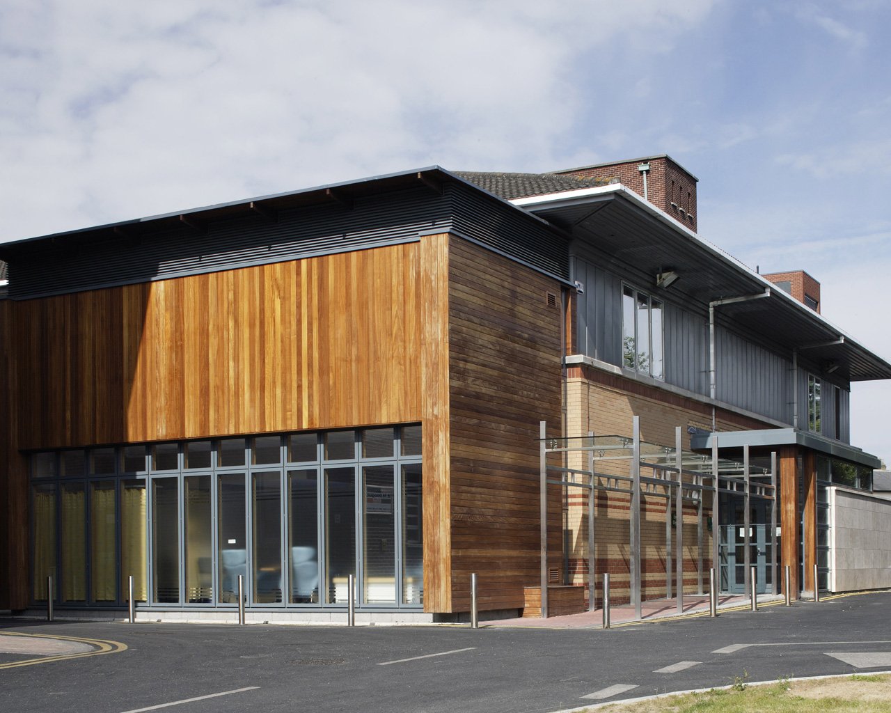 Modern building with wooden and metal exterior, large glass windows, and metal framework outside.