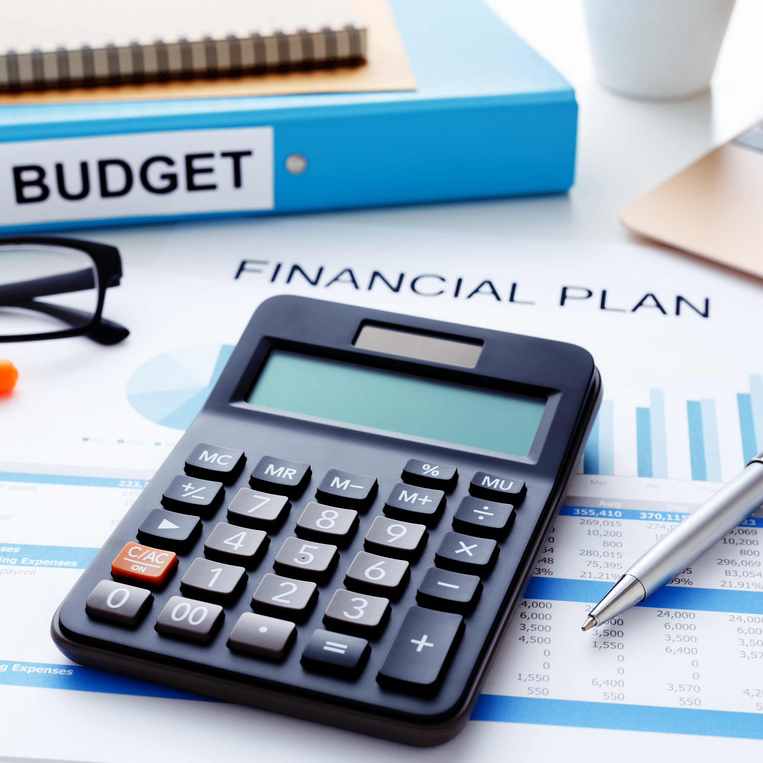 Calculator on financial plan documents with budget folder and pen