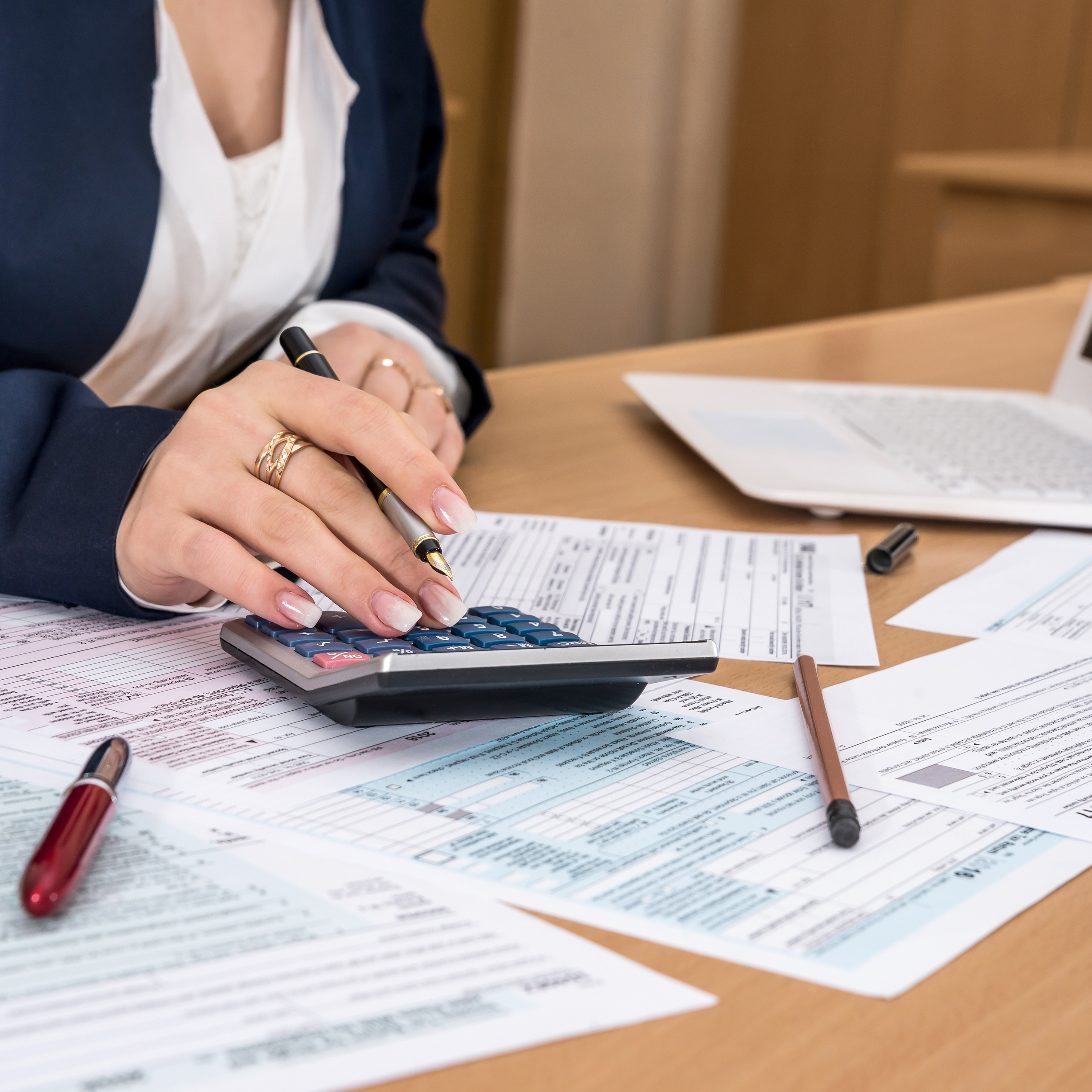 Person using a calculator with tax documents on a desk