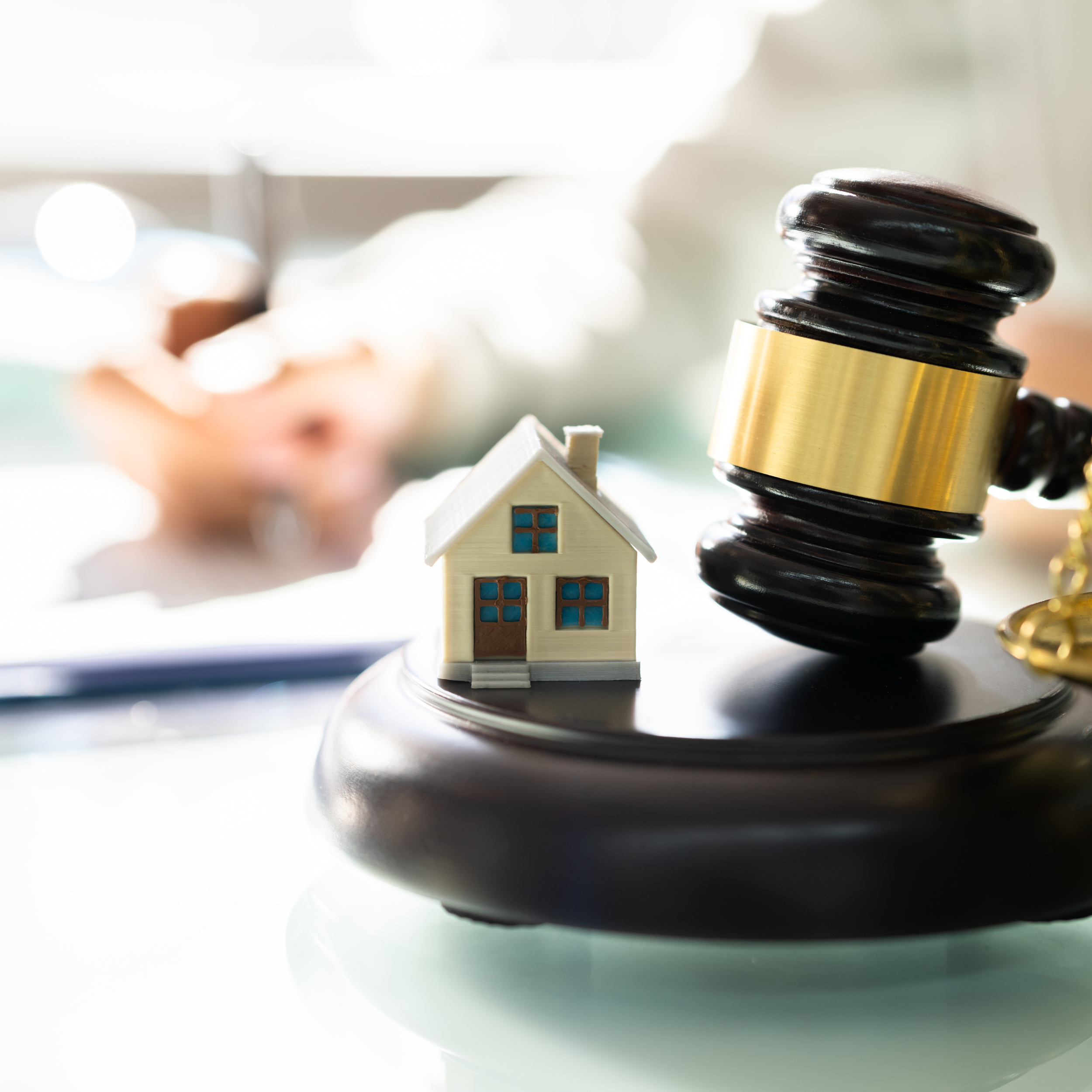 Miniature house next to a judge's gavel on a desk, symbolizing real estate law or property auction.