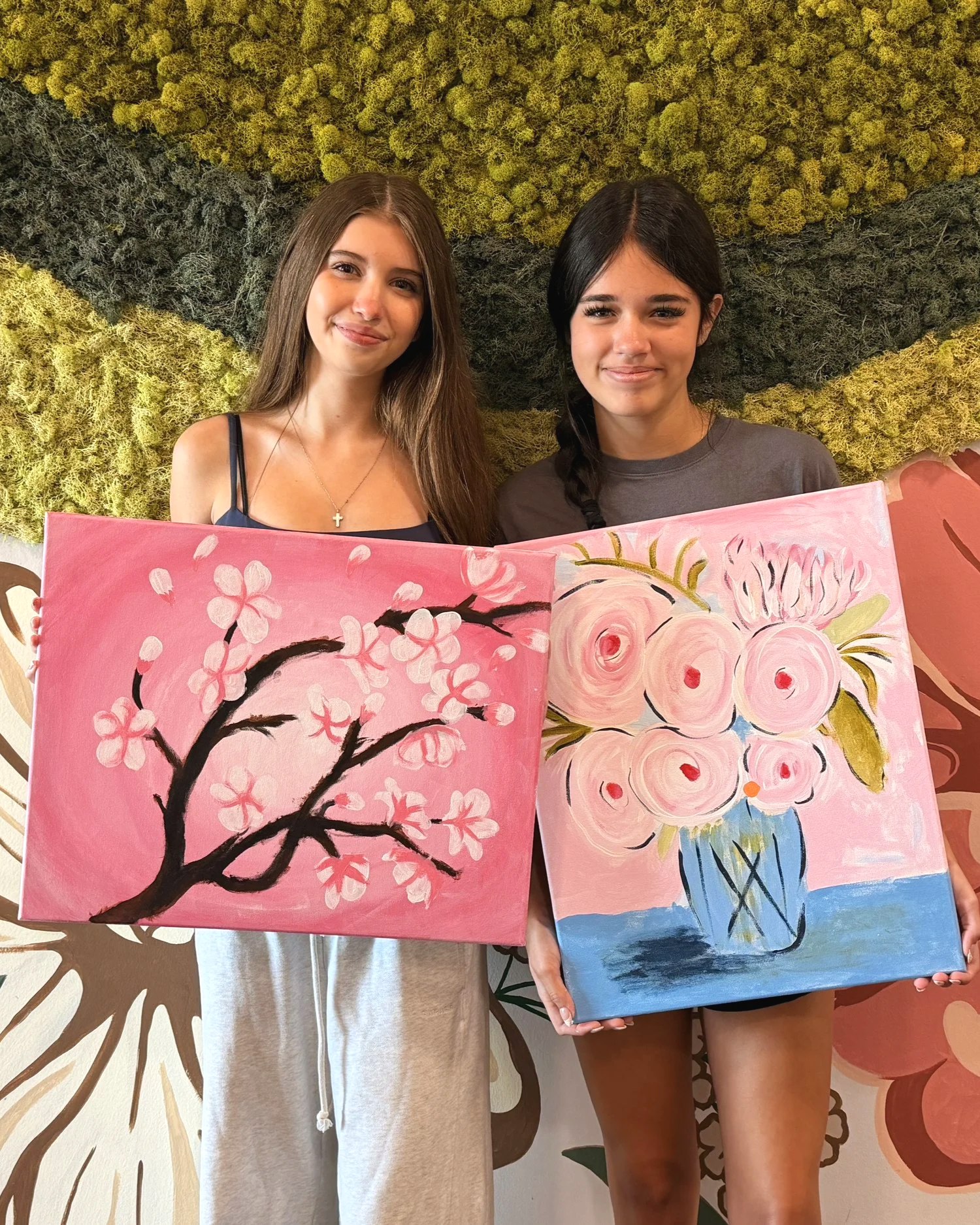 teen age girls holding gorgeous floral canvas paintings