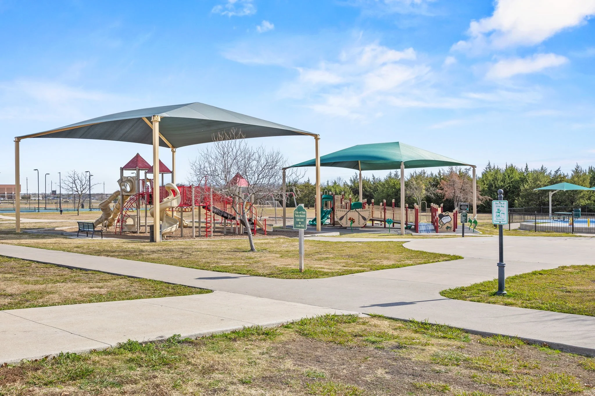 Empty playground with slides and climbing structures under large shade canopies in a park on a sunny day