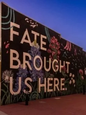 Colorful mural with the text 'Fate Brought Us Here' and floral designs on a dark background.