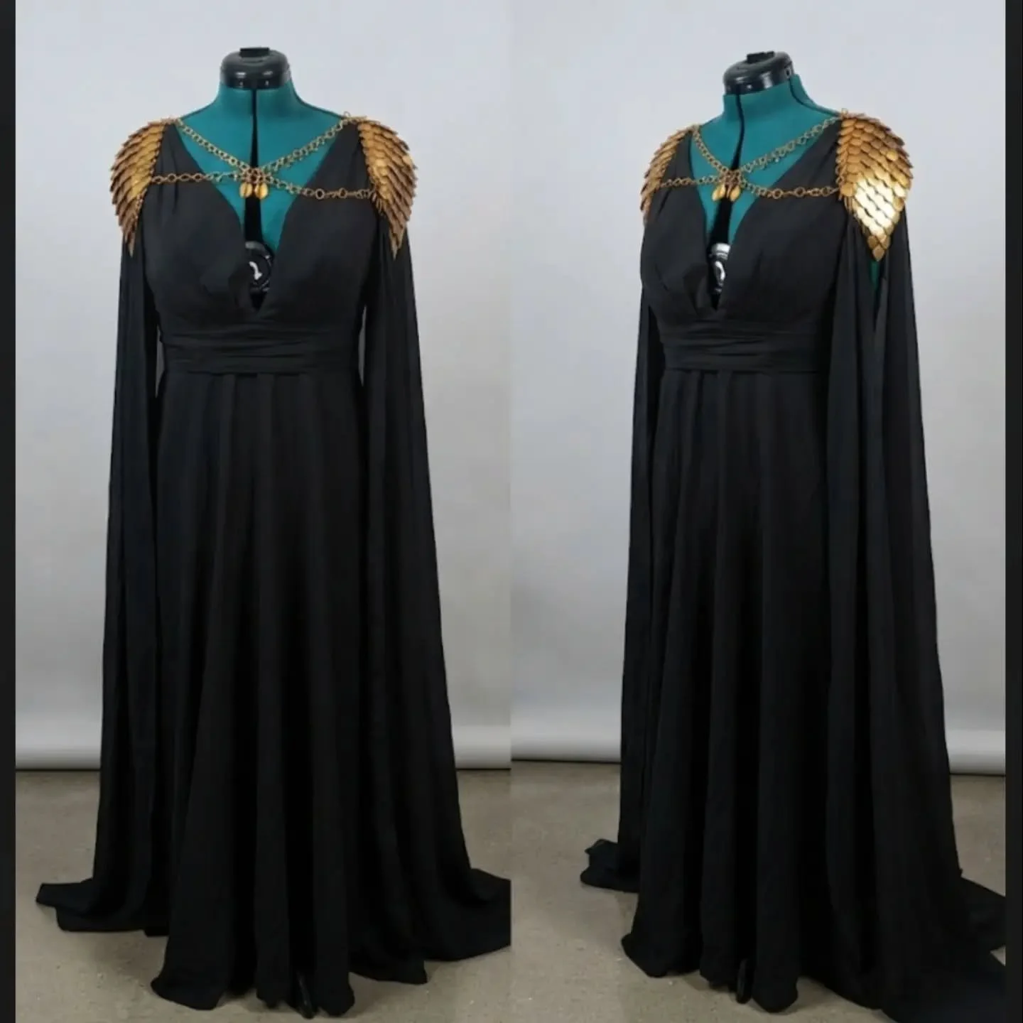 Two fashion mannequins dressed in black evening gowns with gold shoulder embellishments and gold necklace accessories, standing side by side against a plain background.