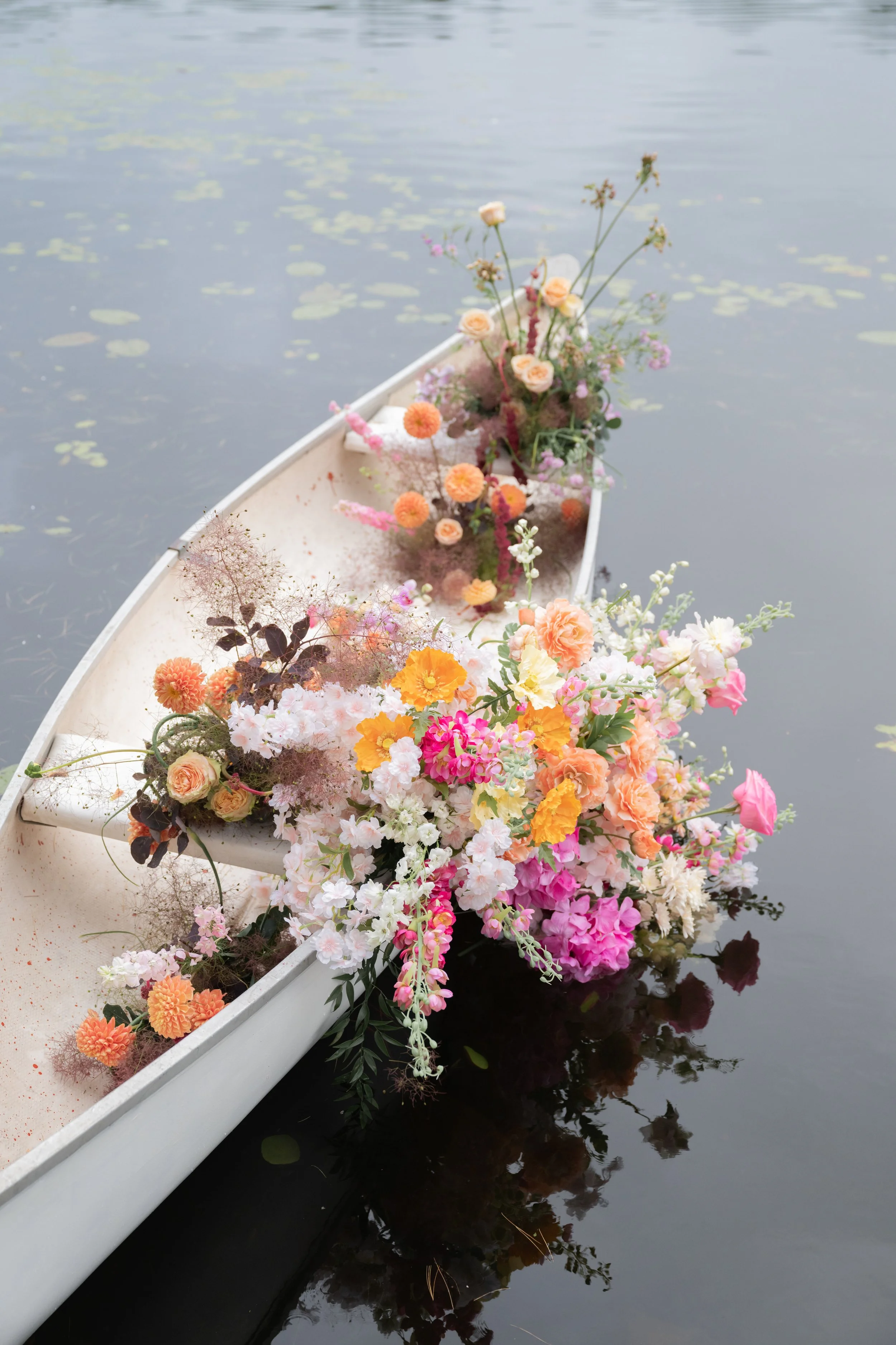 Colorful wedding installation boat with garden roses, ranunculus, and chamomile for a muskoka wedding celebration