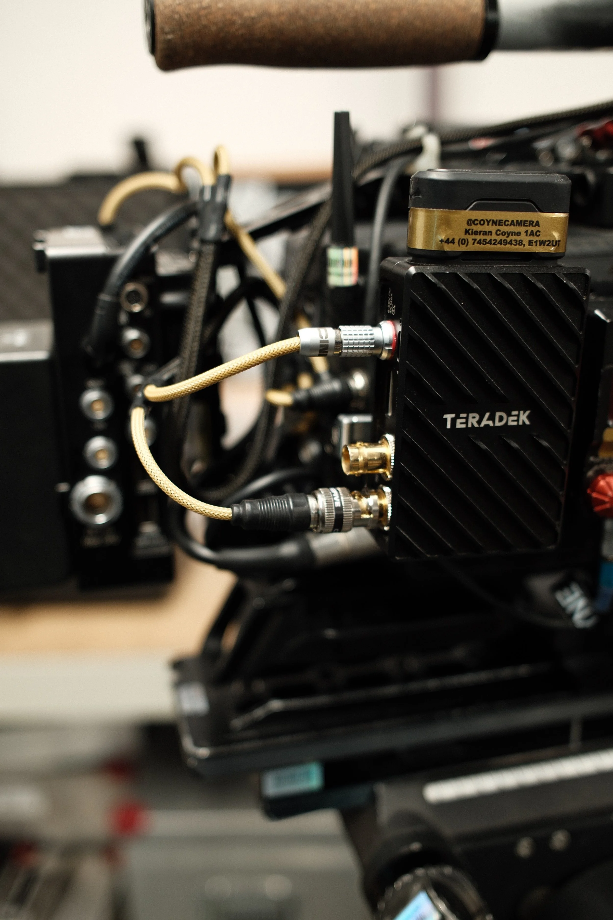 Close-up of camera and audio equipment connected with various cables and adapters in a studio or monitoring setup.