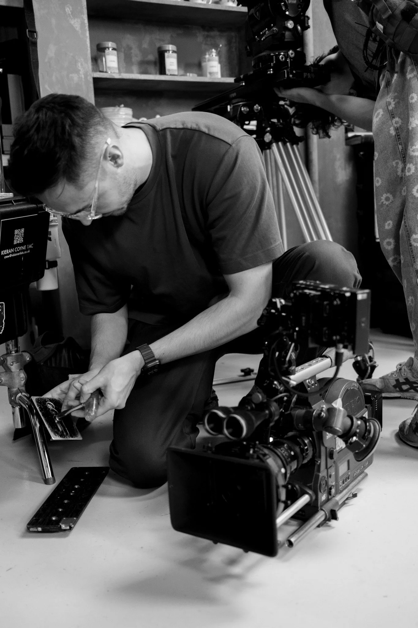 A man working with electronic equipment surrounded by film crew members and cameras in a studio.
