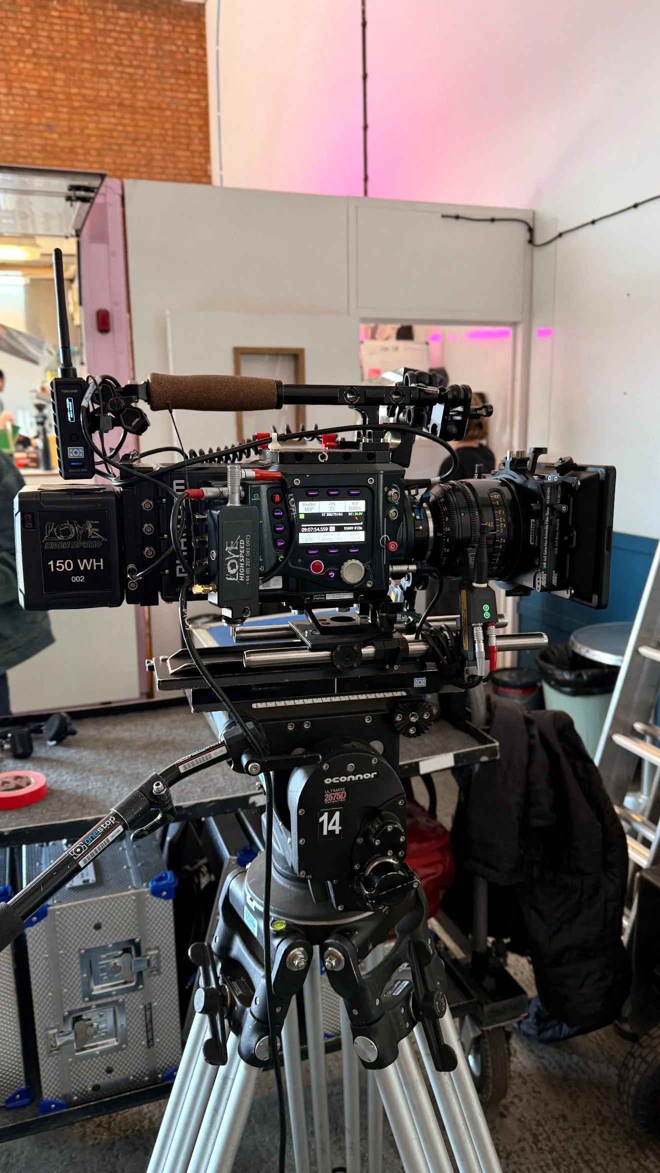 Professional movie camera mounted on tripod in a film set or studio environment.