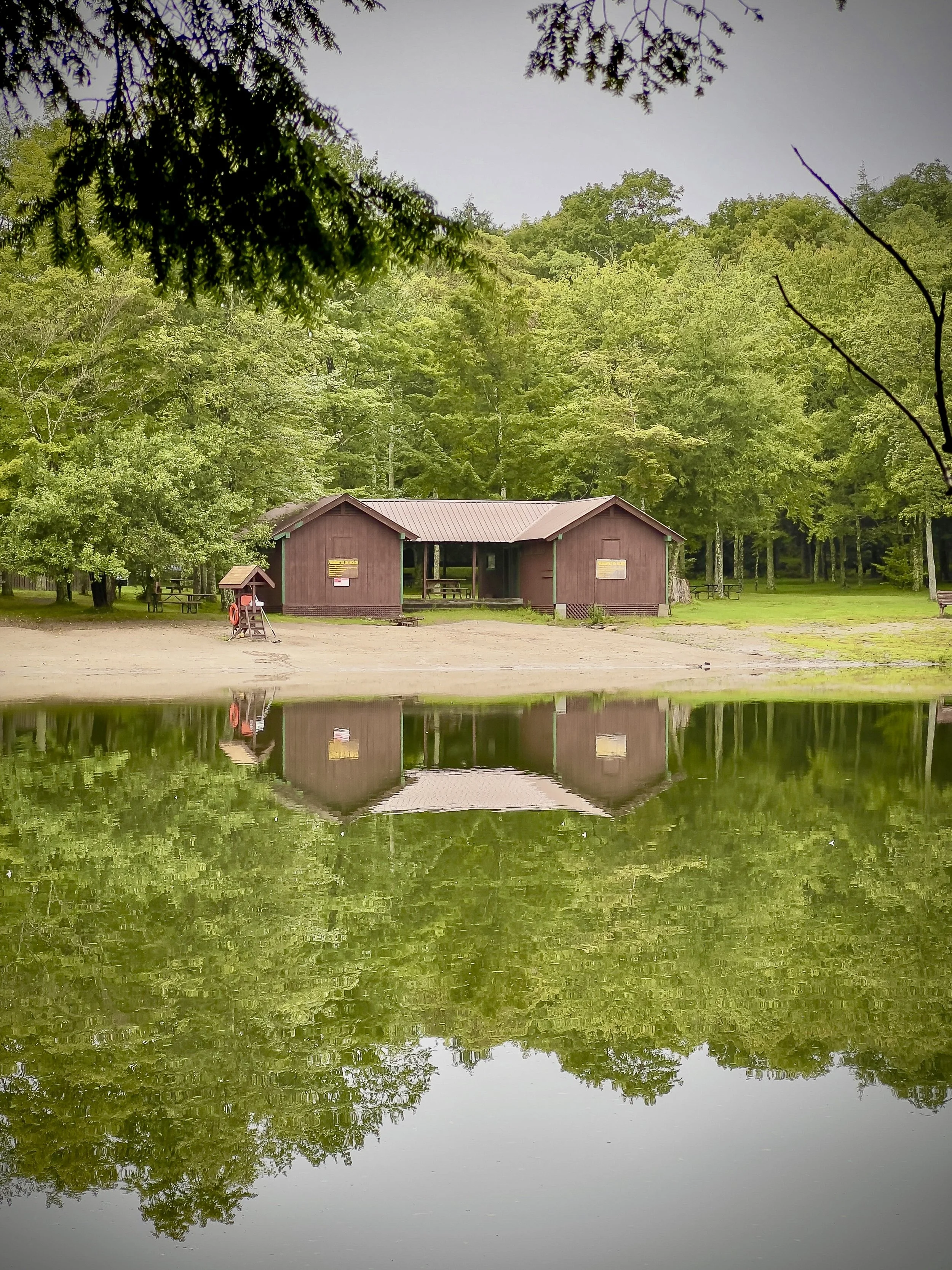 Still lake reflecting a cabin and treeline, an example of noticing detail in landscape photography