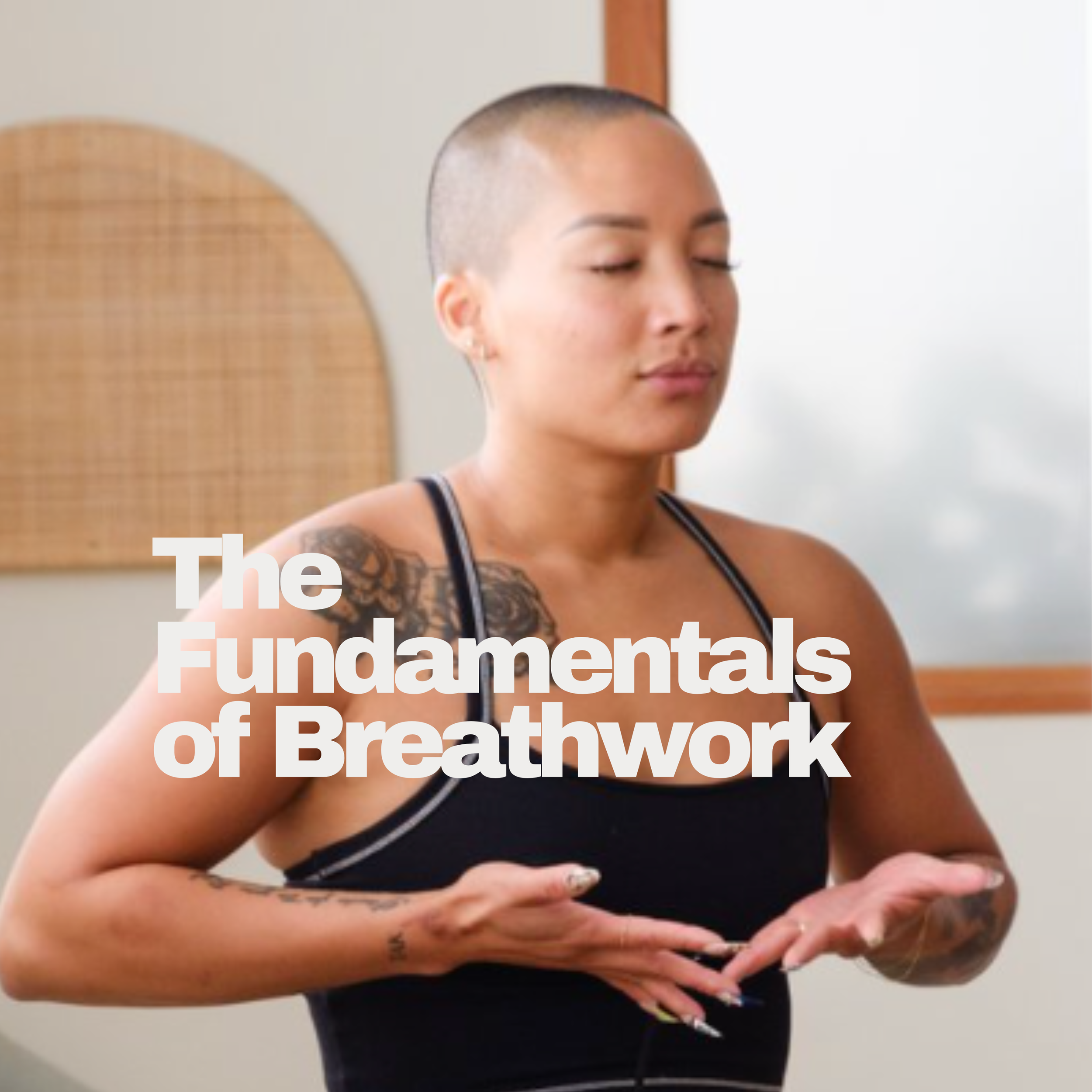 A woman with a shaved head practicing breathwork, with her eyes closed and hands in a relaxed position, in a room with neutral walls and a wooden frame mirror.