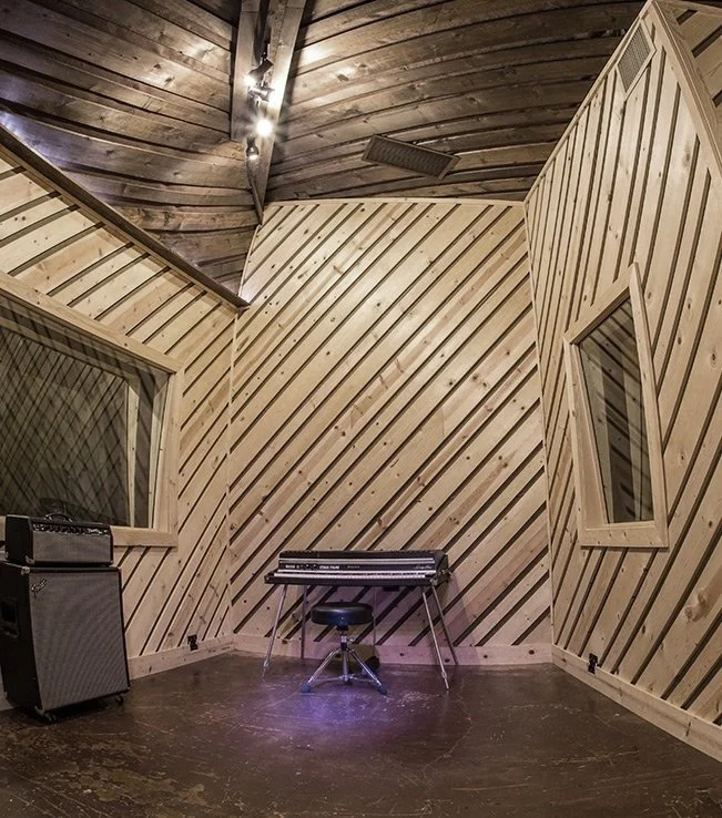 The live room, empty and lit low — diagonal shiplap walls on every surface.
