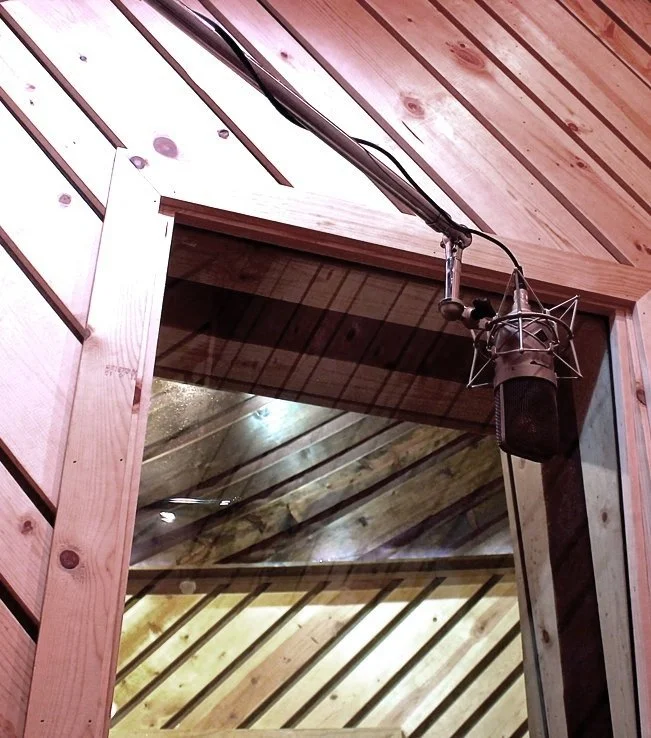 A ribbon microphone hung under a timber frame in the live room.