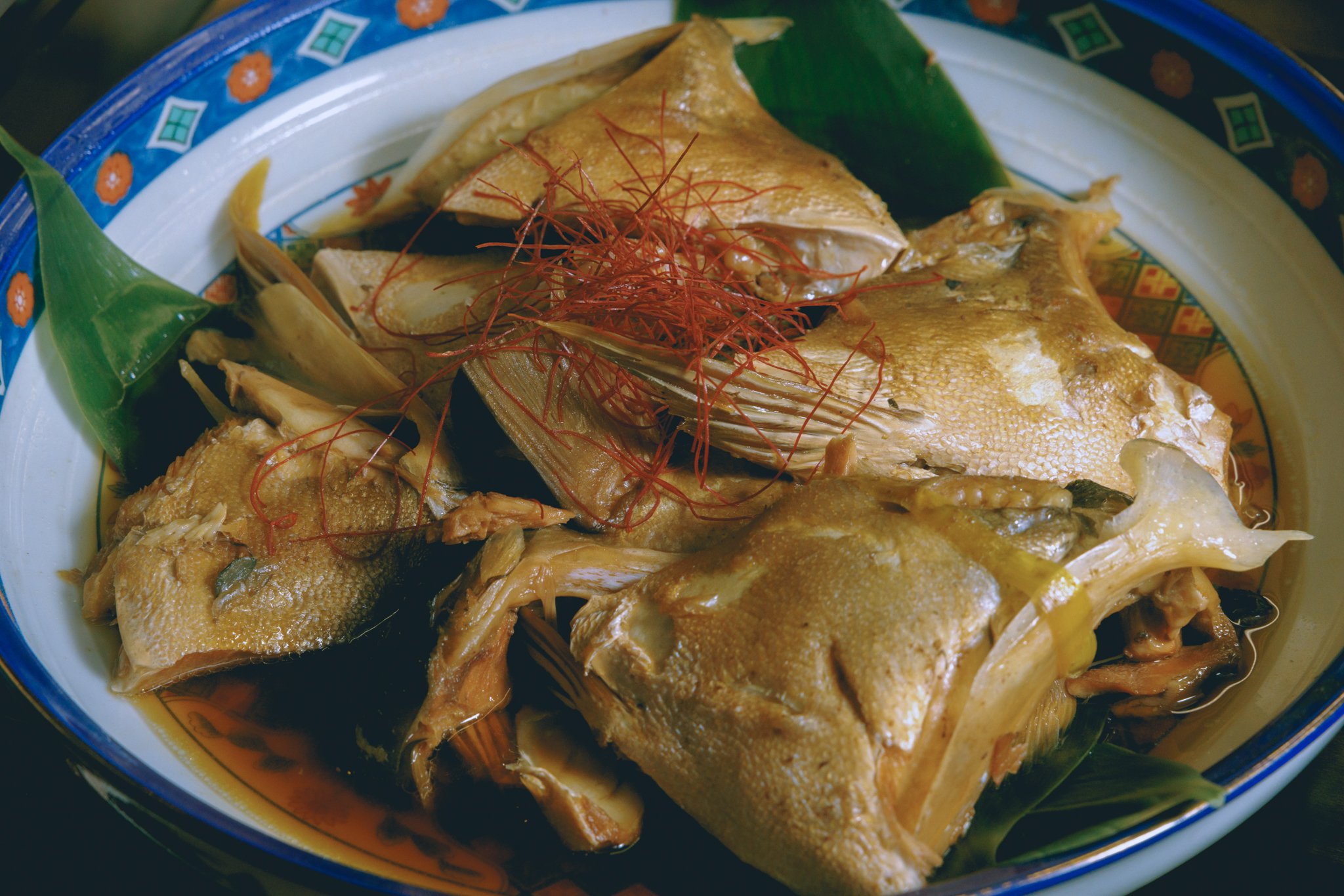 Braised fish dish with garnish on decorative plate