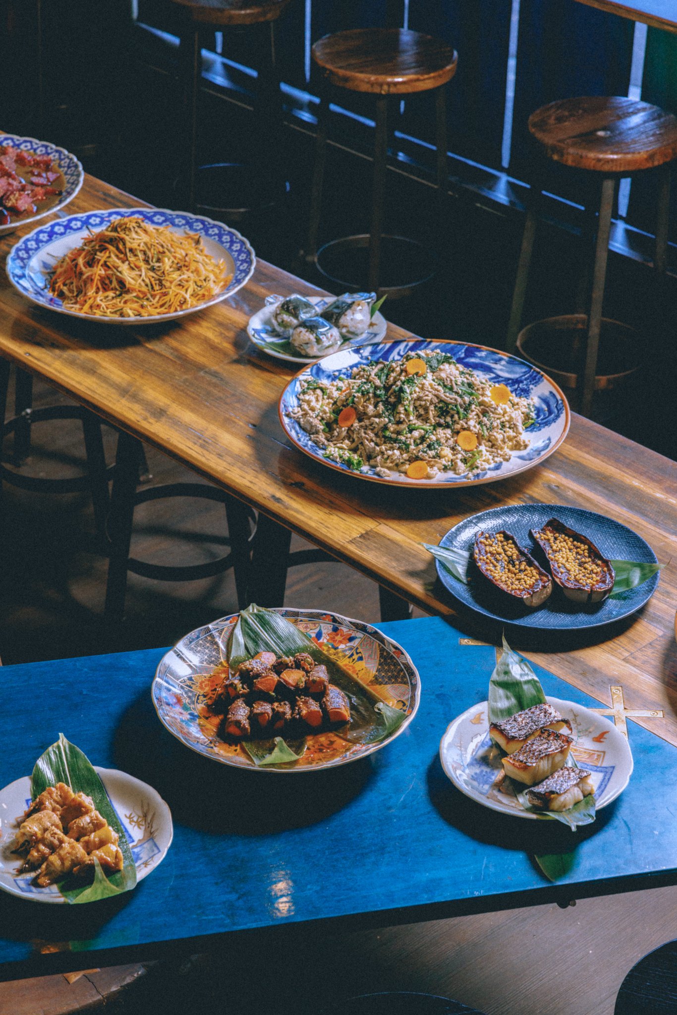 Assorted Japanese dishes on wooden tables in a restaurant setting.