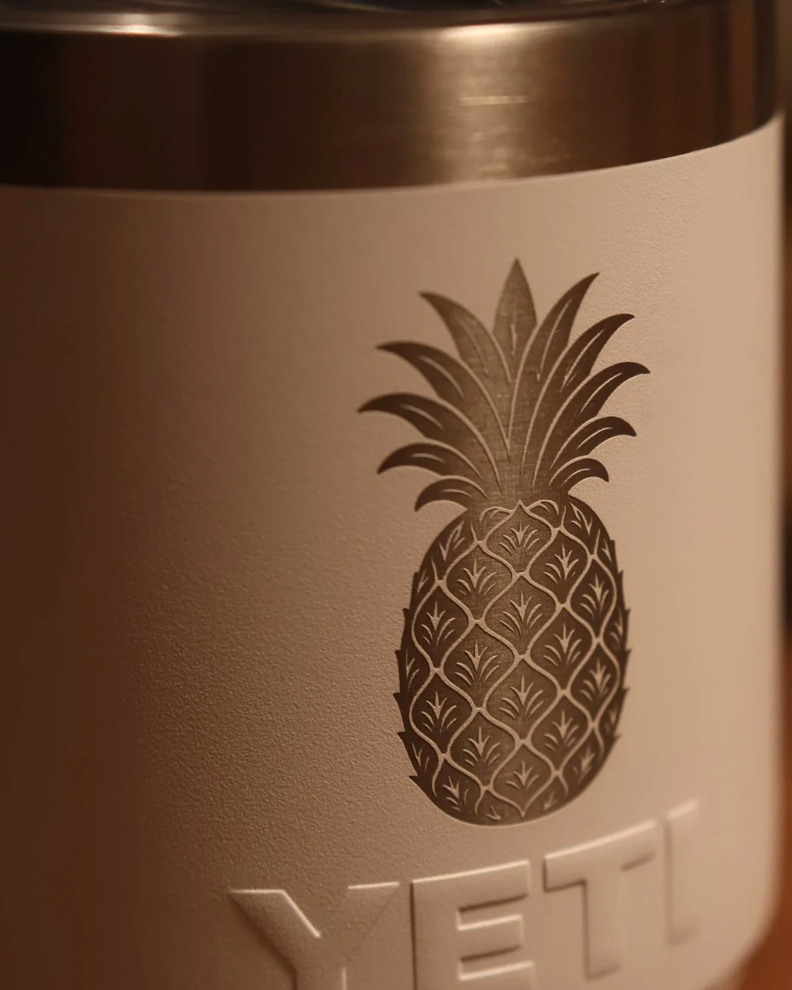 Close-up of a laser engraving of a pineapple on a metal tumbler with a white background.