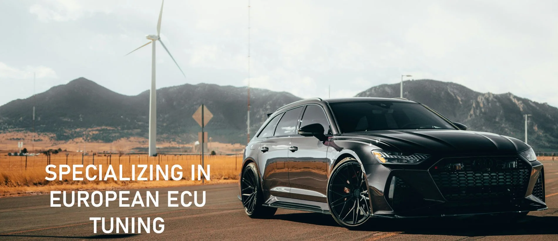 Black modern station wagon car on an open road with wind turbines and mountains in the background, overlaid with white text reading 'Specializing in European ECU Tuning'.