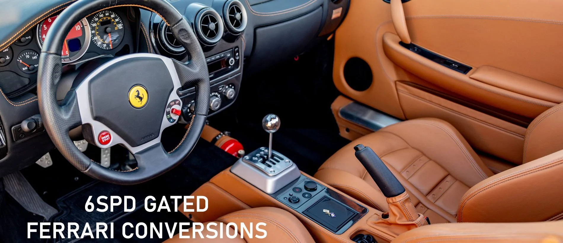 Interior of a luxury sports car with tan leather seats, a racing steering wheel with Ferrari logo, and a gear shift. The dashboard displays gauges and controls, with a small fire extinguisher visible on the floor.