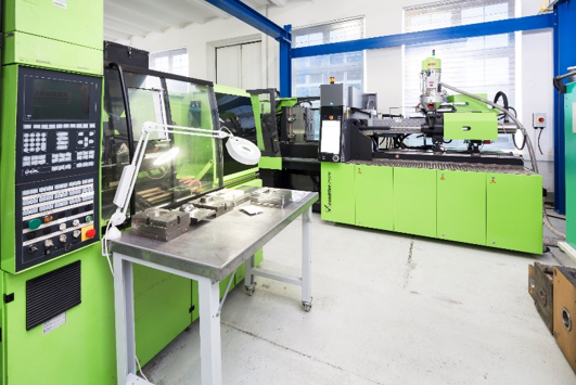 Industriemaschine in einer Fabrikhalle, mit grüner Farbe und Steuerungspanel.