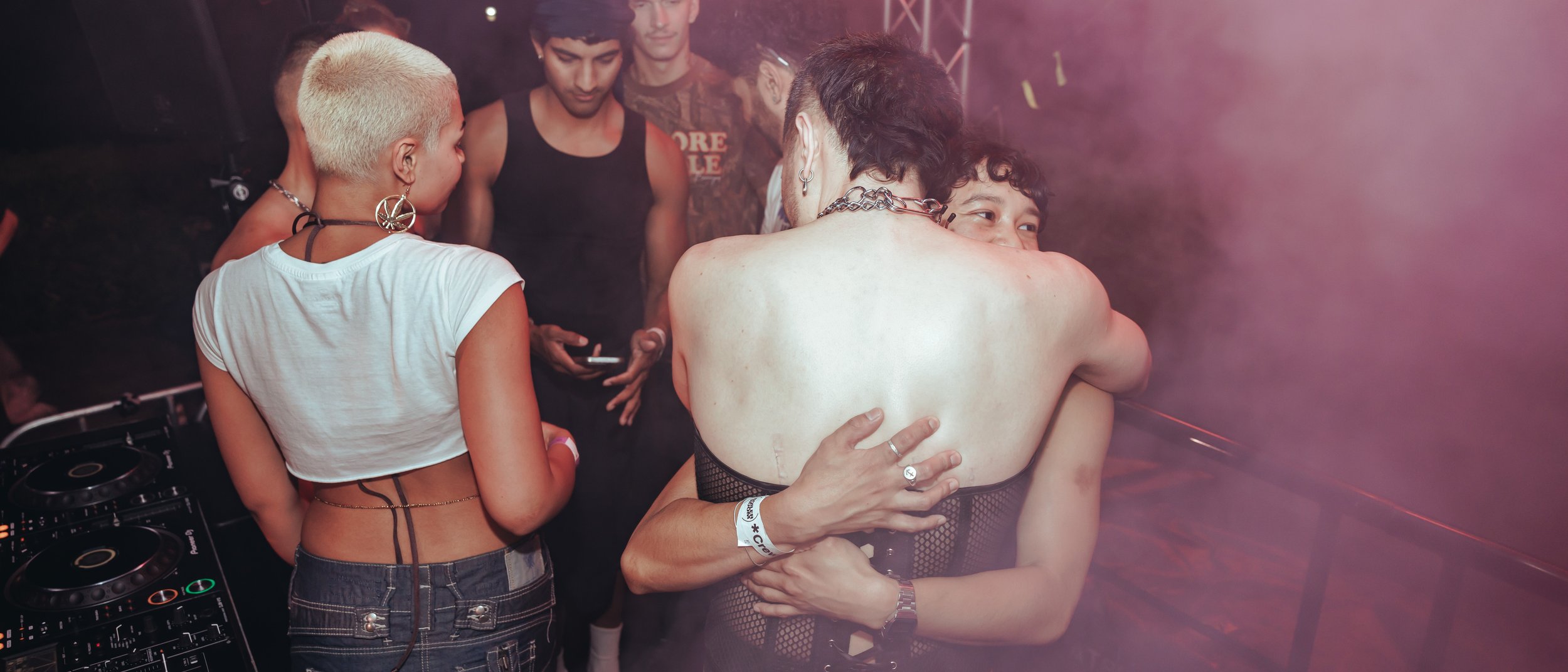 People socializing at a nightclub with DJ equipment visible.