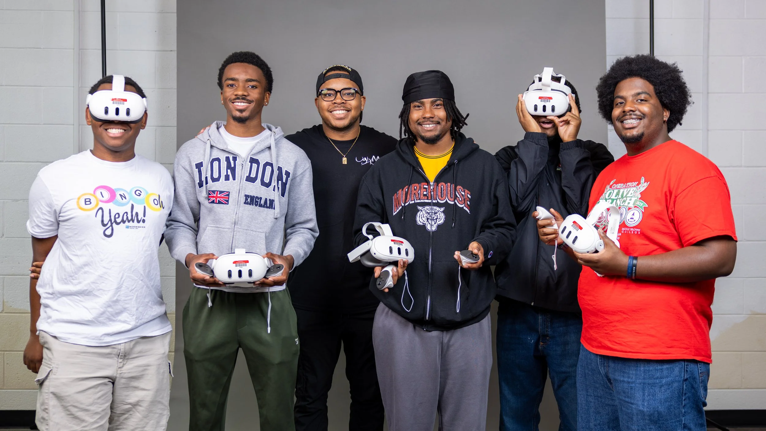 A podcast recording session in progress with two hosts at a table, wearing headphones and speaking into microphones. Camera and lighting equipment are visible, capturing the session. The background features a wooden wall with a circular red logo and a warm, ambient setting.
