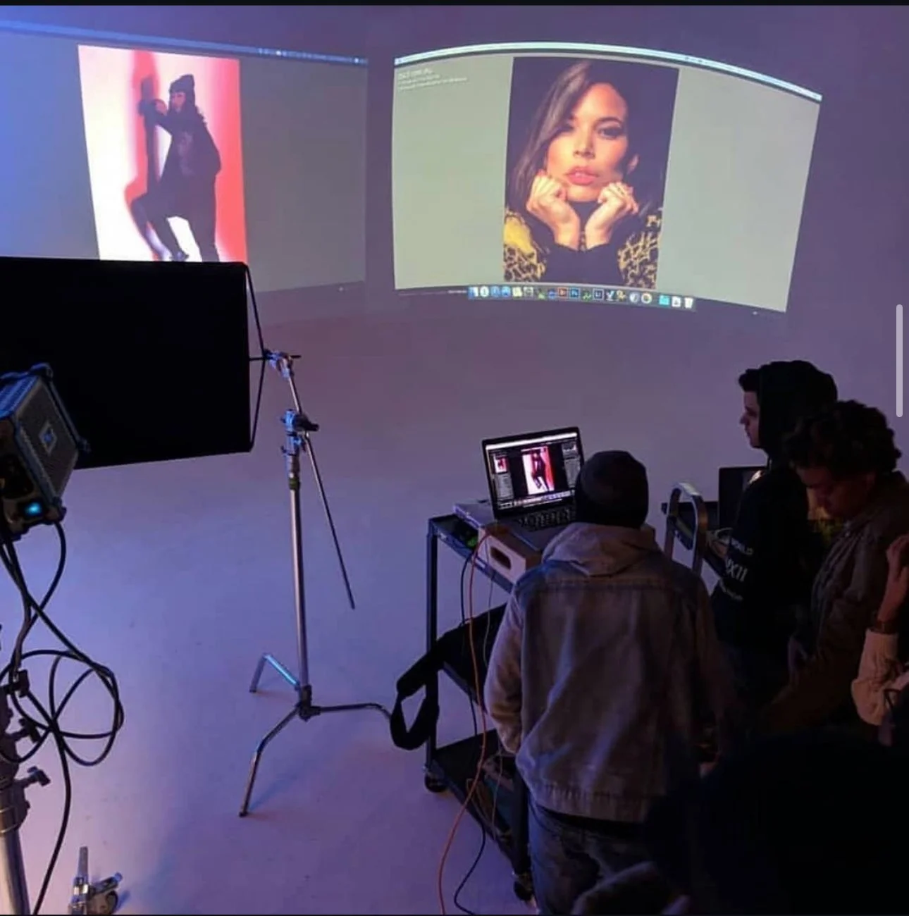 Photography studio setup with monitors displaying portrait images and people reviewing them.
