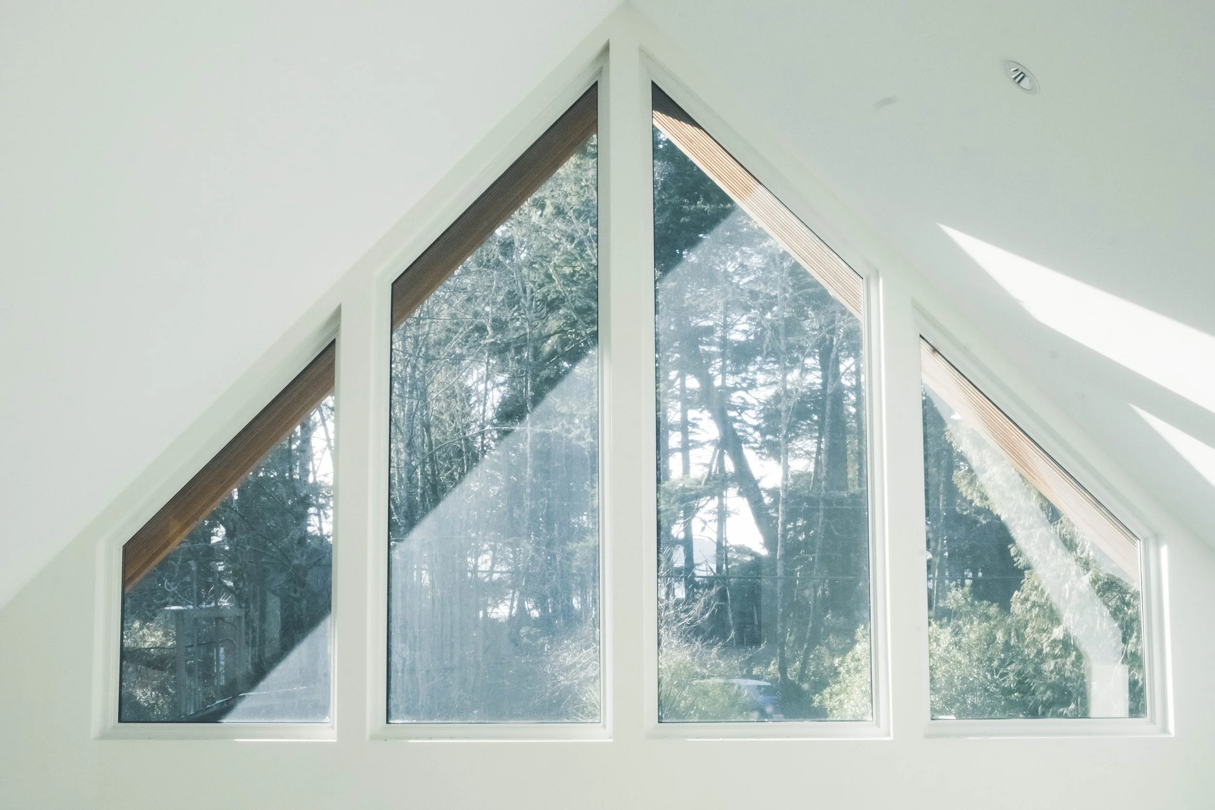 Large triangular window with four panes showing trees outside.