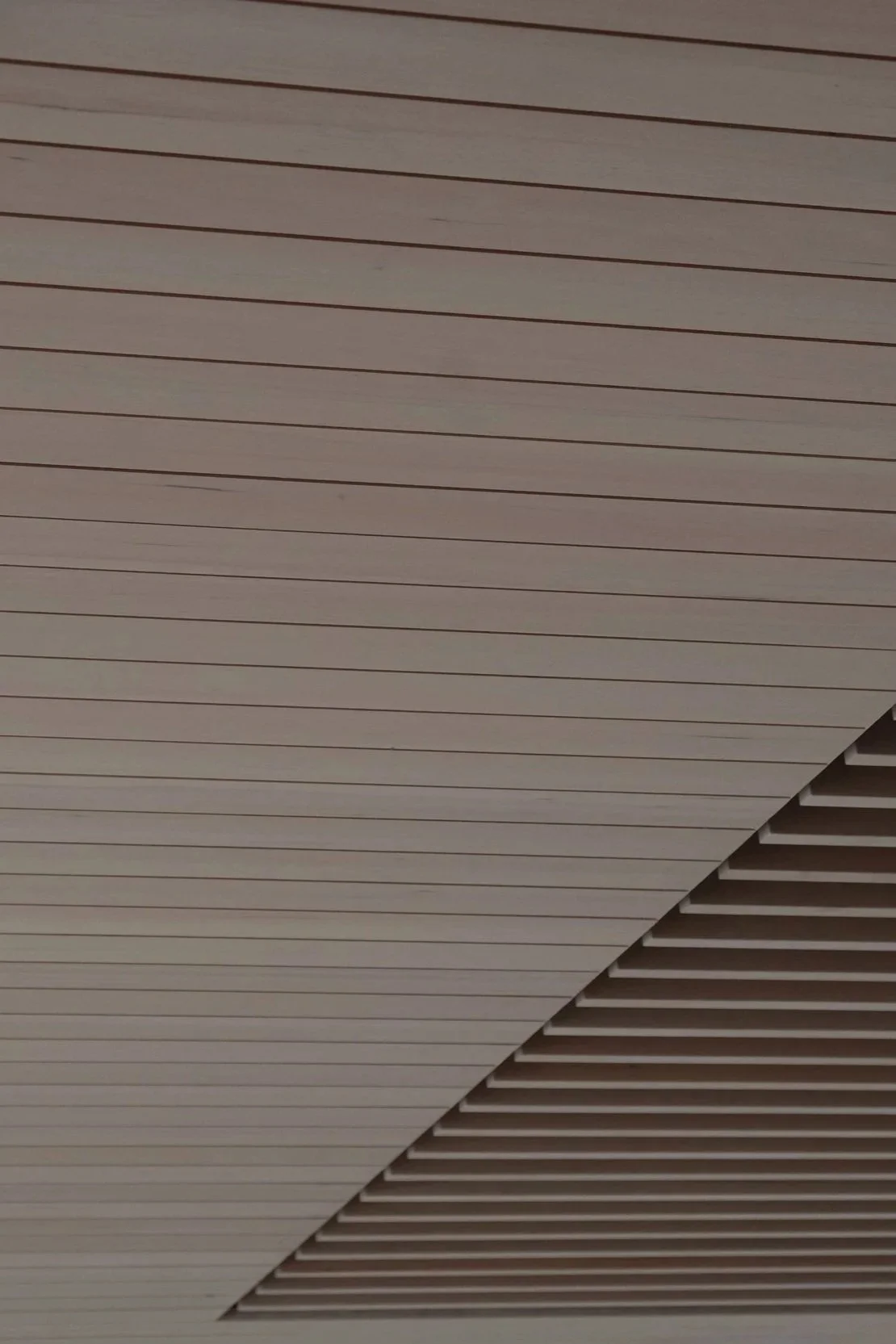 Ceiling with linear wooden panels and slats.