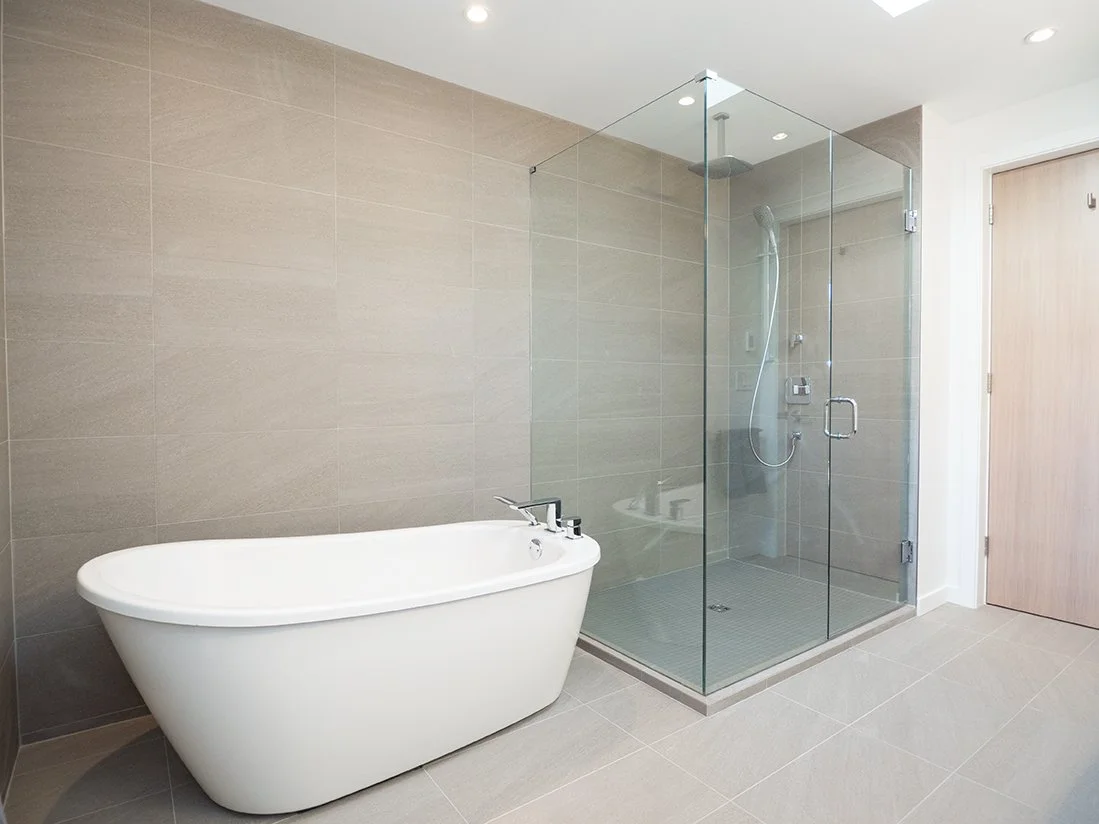 Modern bathroom with a freestanding bathtub and a glass-enclosed shower area in neutral tones.