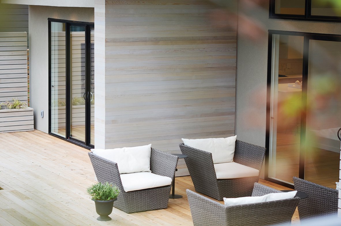 Outdoor patio with wicker chairs and white cushions, potted plant, and west-facing sliding glass door.