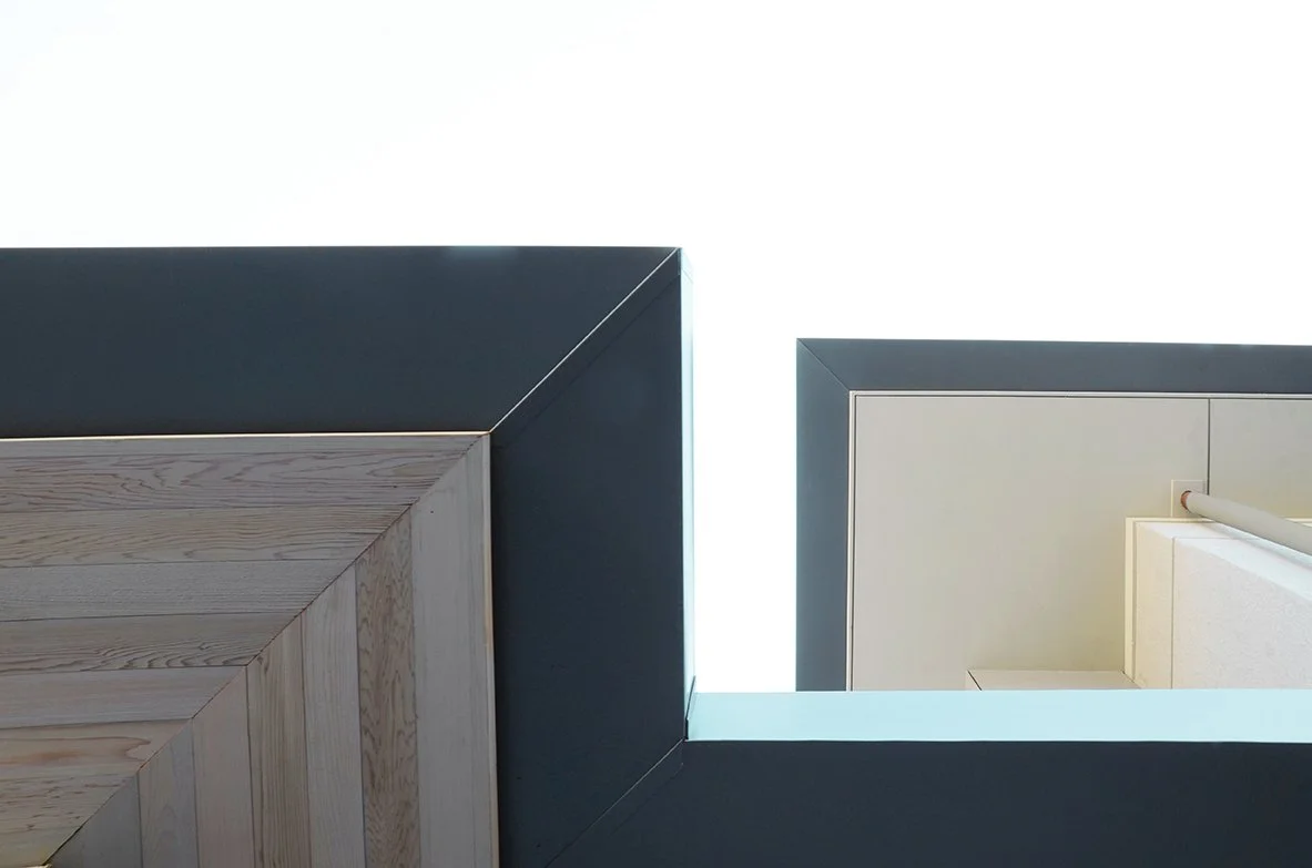 Looking up at a modern building's geometric facade from the ground, showing sharp angles and contrasting materials.