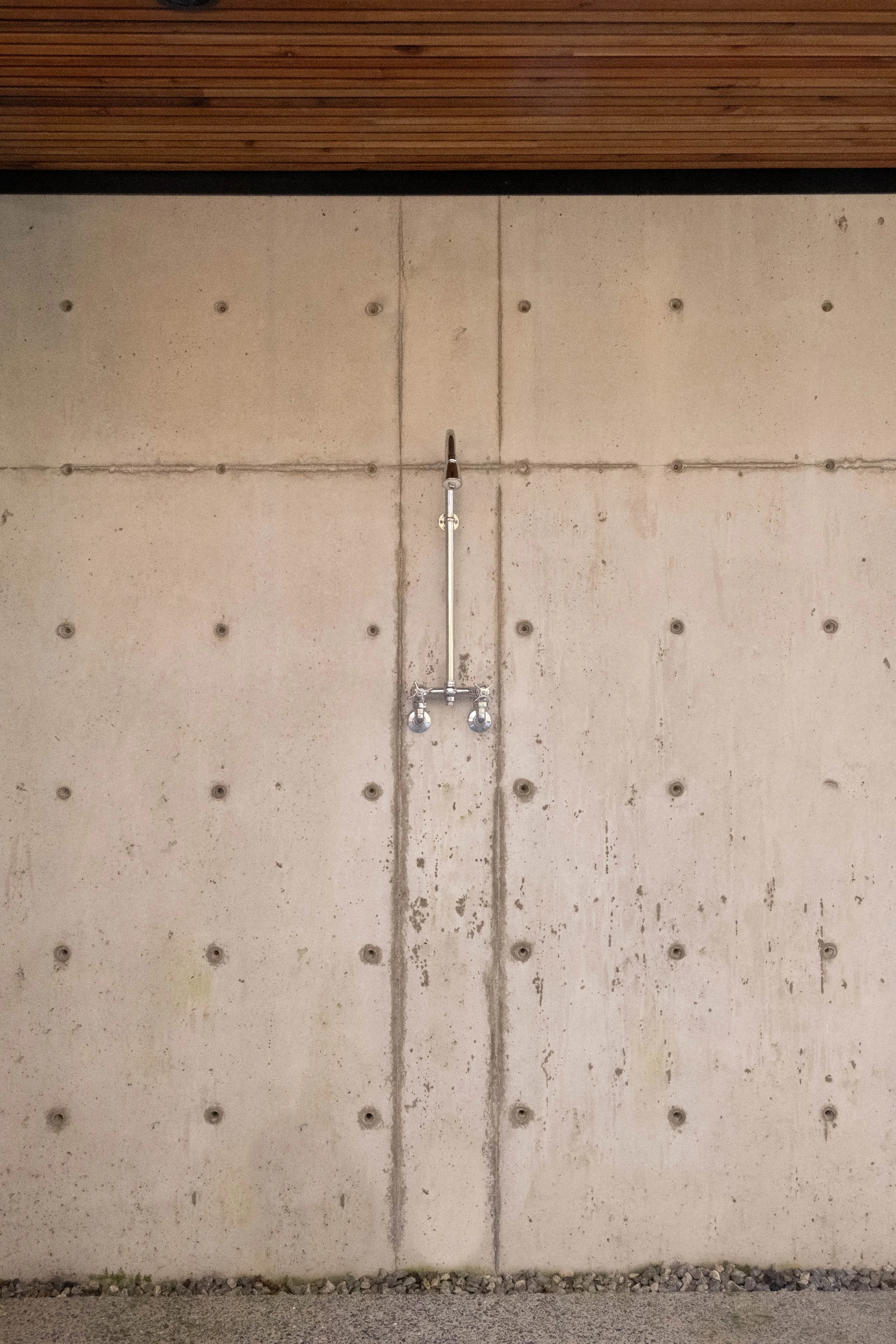 Concrete wall with exposed piping and two water shutoff valves in the center
