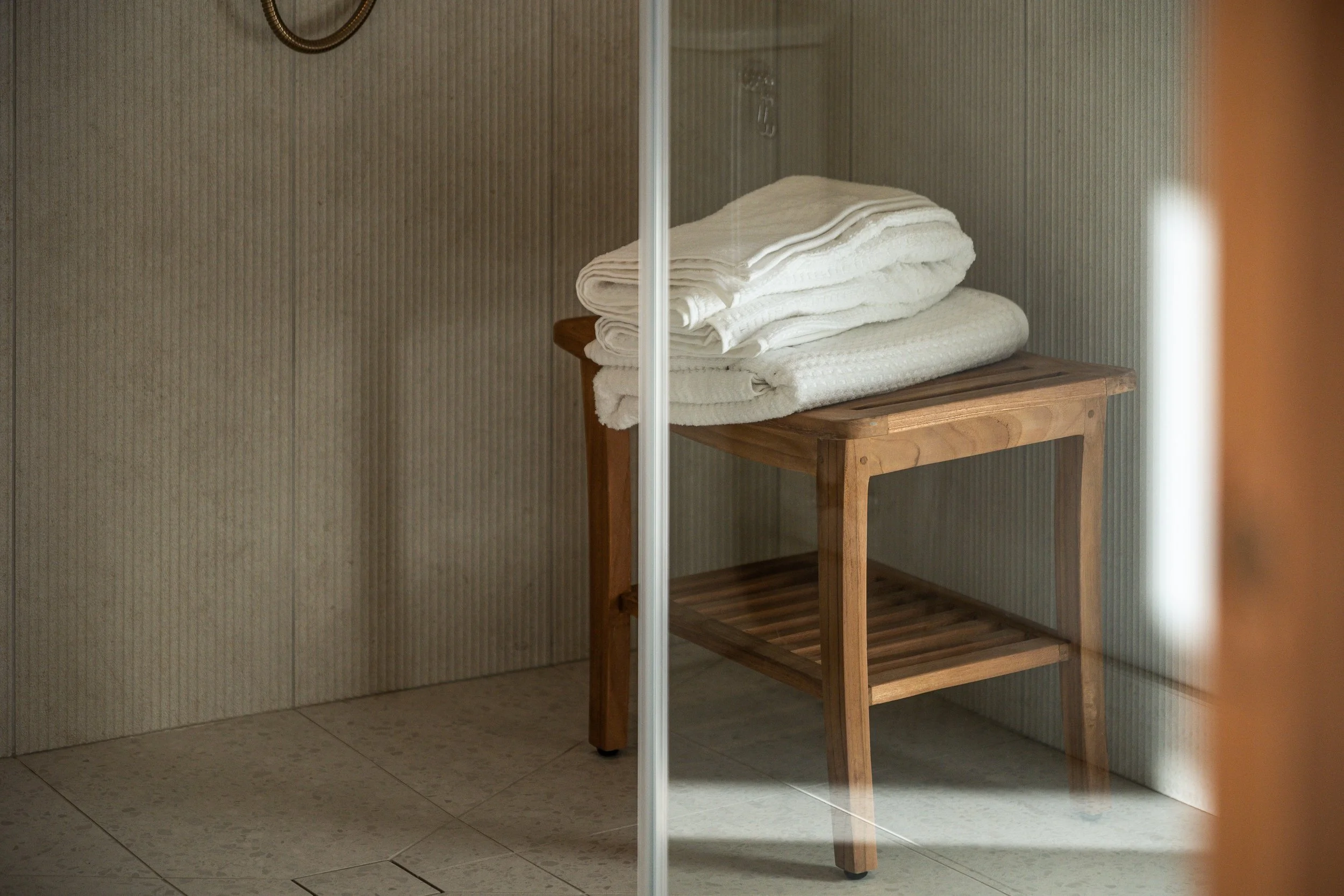 A small wooden table holding neatly folded white towels in a bathroom or spa setting.