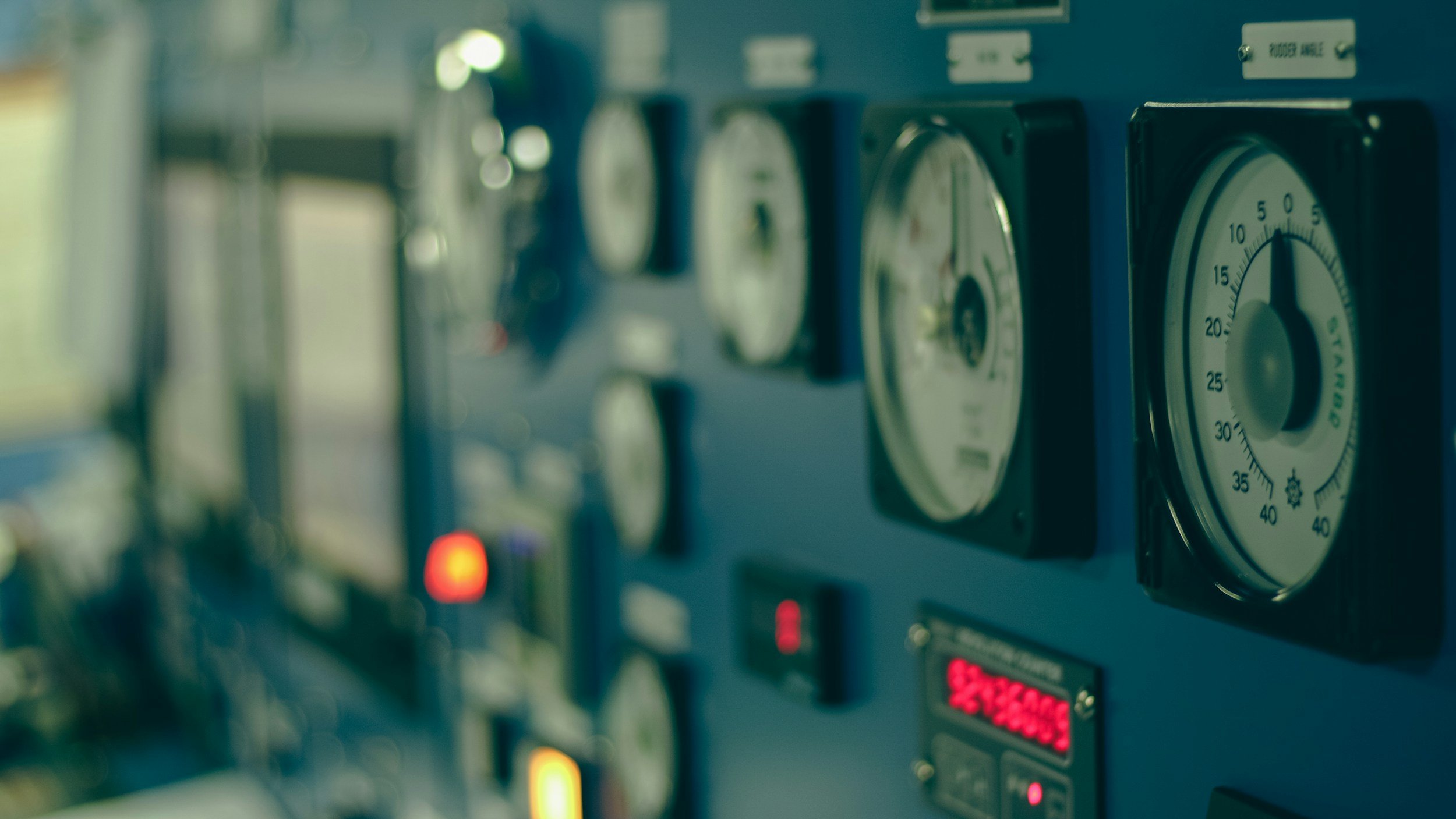 Close-up of a row of analog gauges on a control panel, showing various measurements with one gauge clearly visible.
