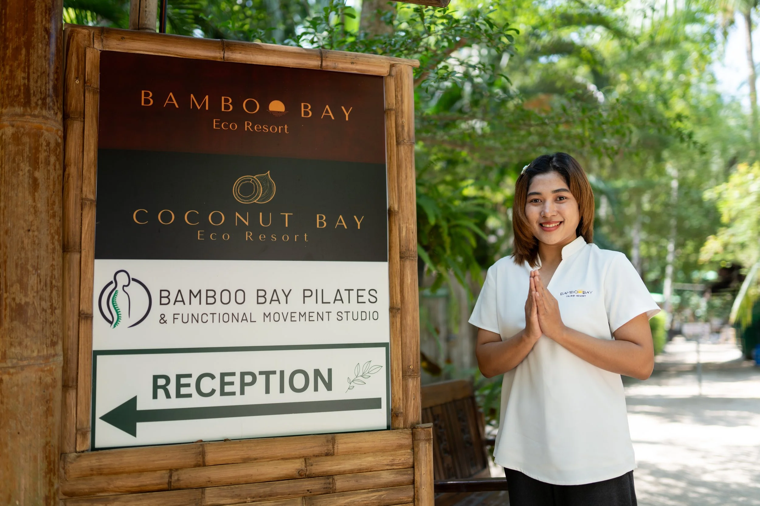 Ready to service you with a smile at Bamboo Bay Eco Resort, with trees and green foliage in the background, in Koh Phangan